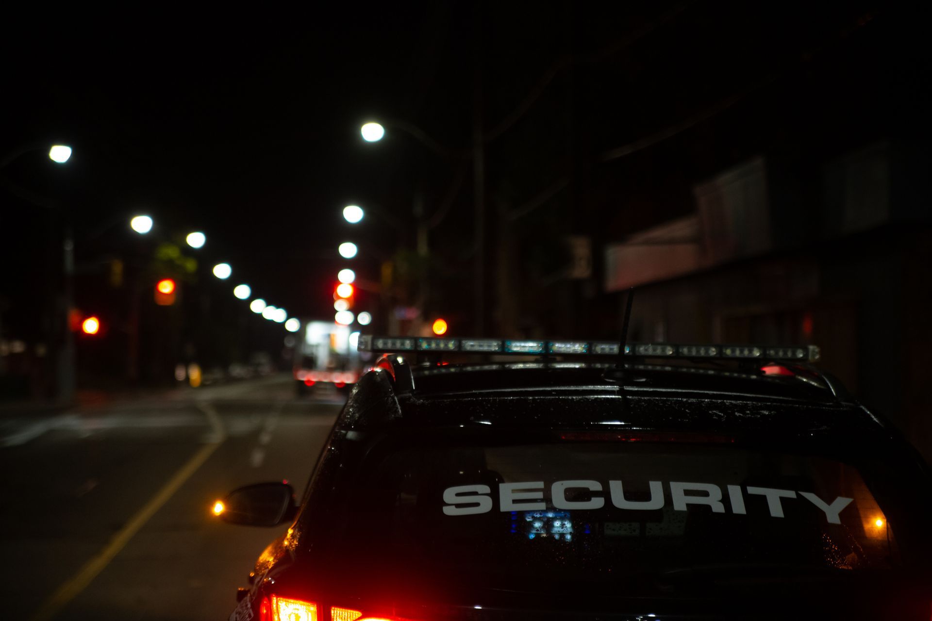 Security vehicle patrolling a dark city street at night.