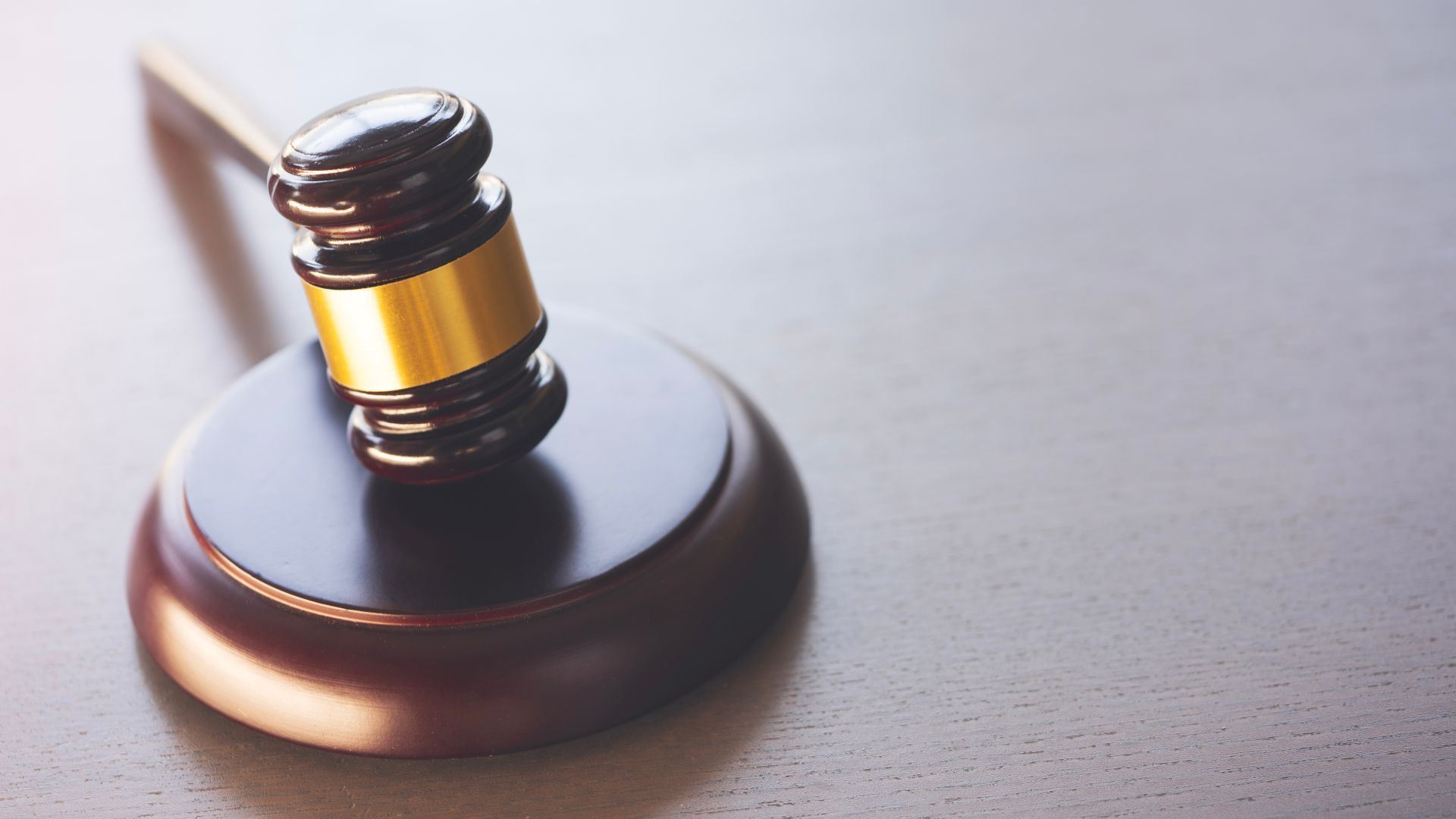 Wooden gavel on a round block, resting on a gray surface.