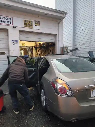 A man is getting into a car in front of a garage.