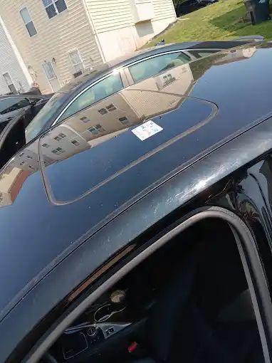 A black car with a sunroof is parked in front of a house.