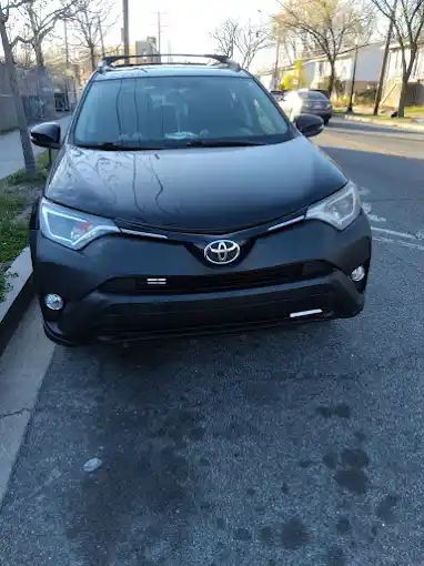 A black toyota rav4 is parked on the side of the road.
