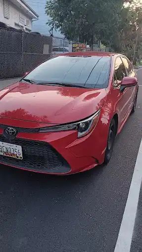 A red toyota corolla is parked in a parking lot.