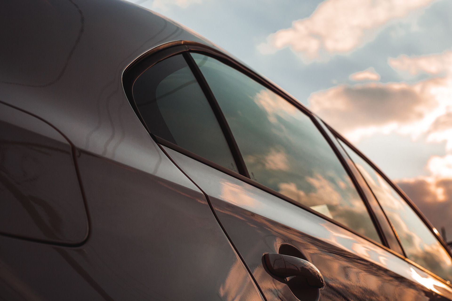 A car is parked in front of a cloudy sky at sunset.