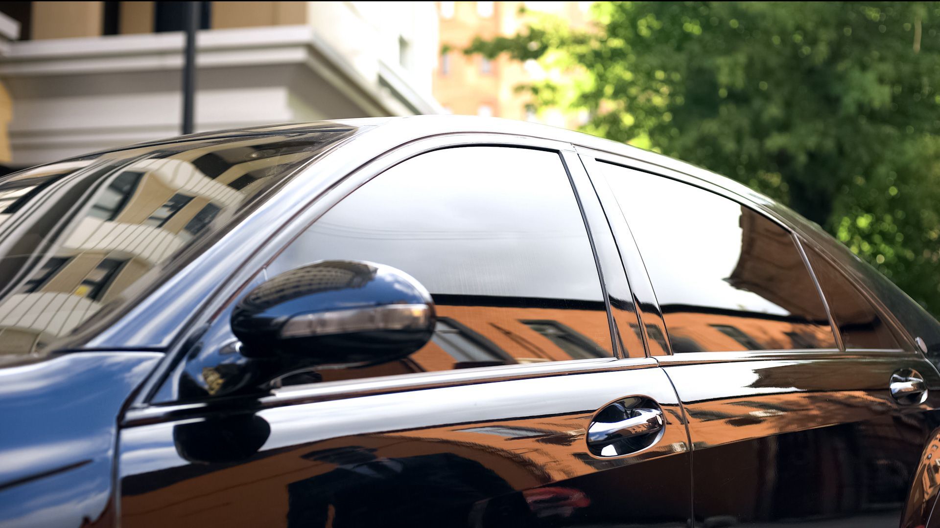 A black car is parked in front of a building.