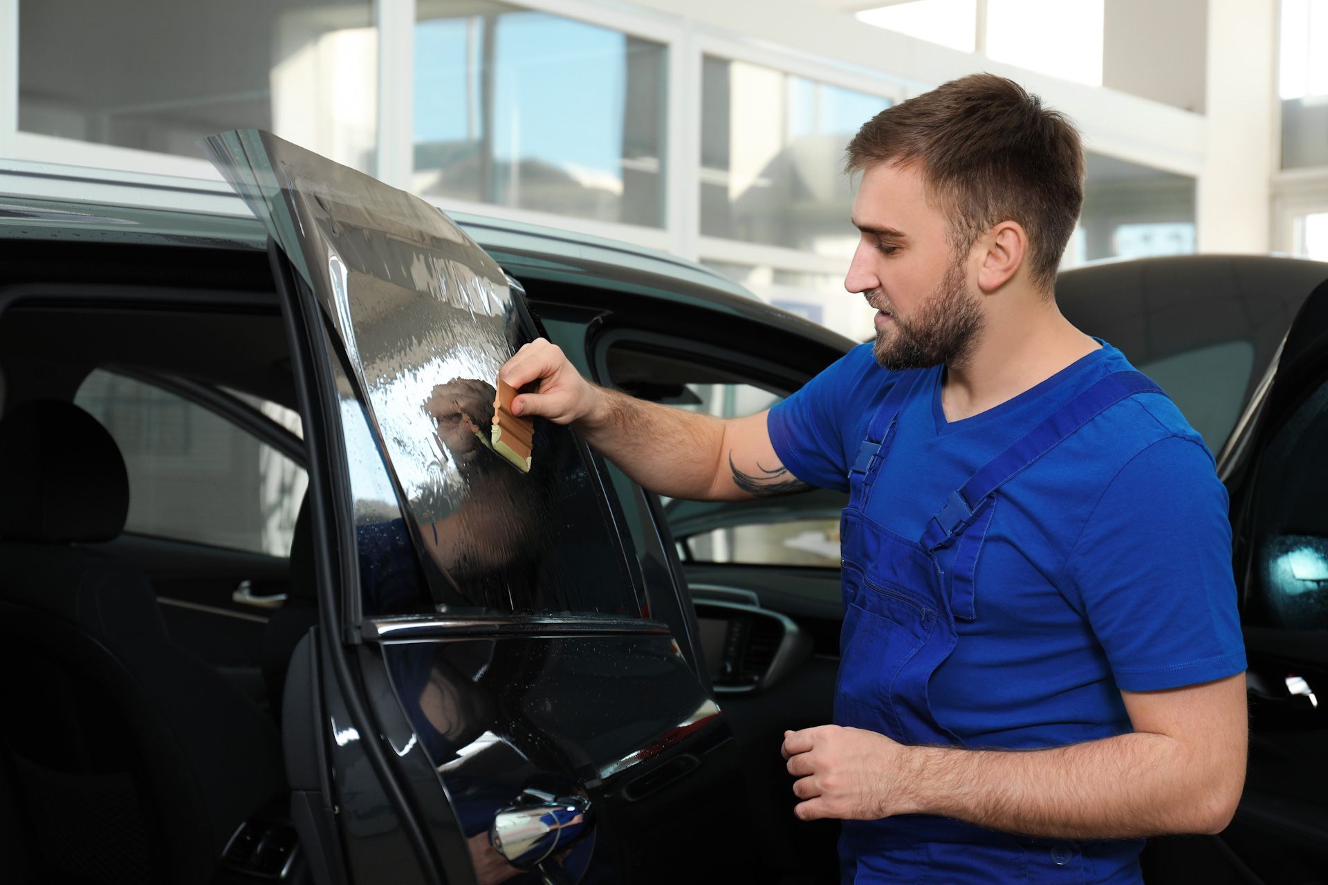 A man is applying window tinting to a car window.