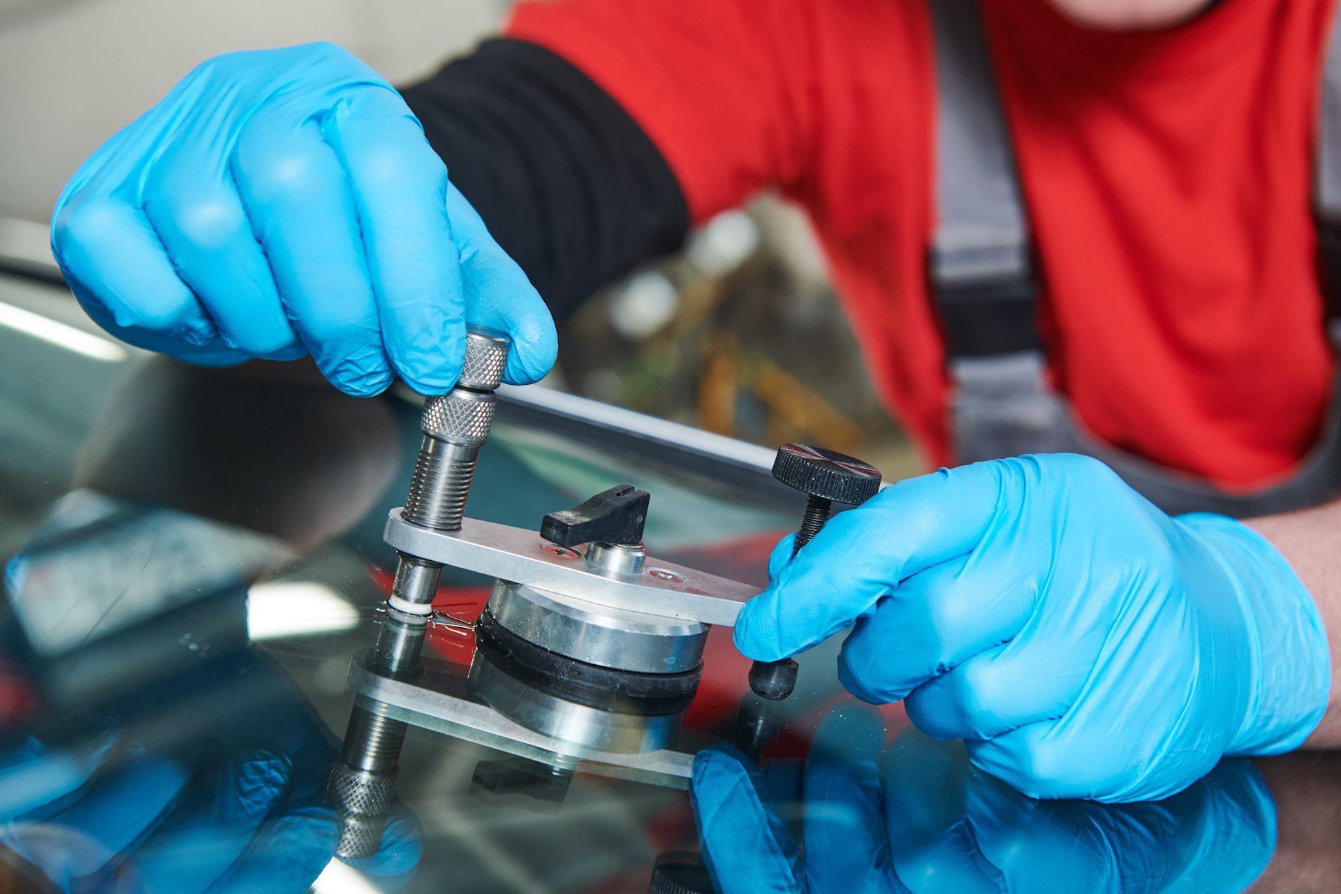 A person wearing blue gloves is repairing a windshield.
