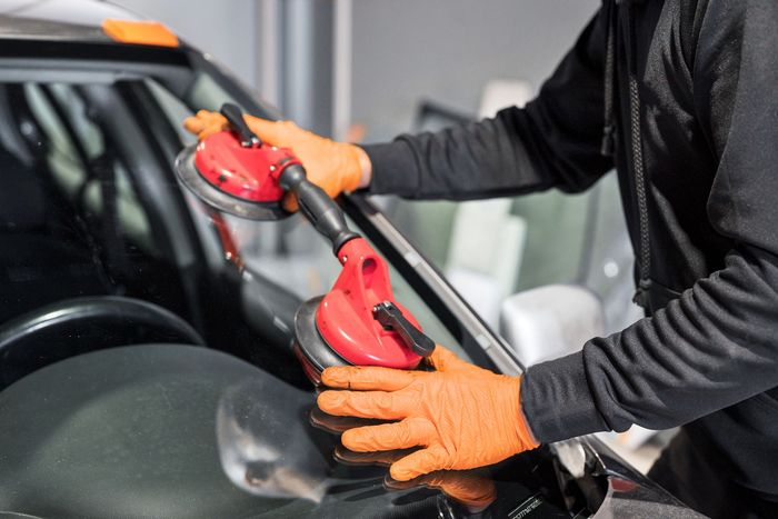 A man is installing a windshield on a car.