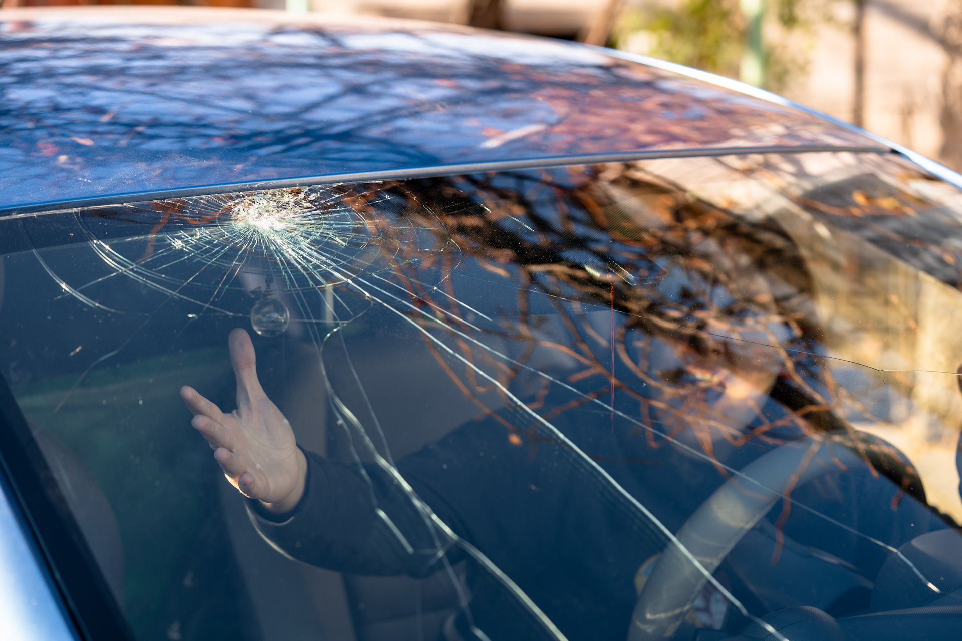 A man is sitting in a car with a broken windshield.