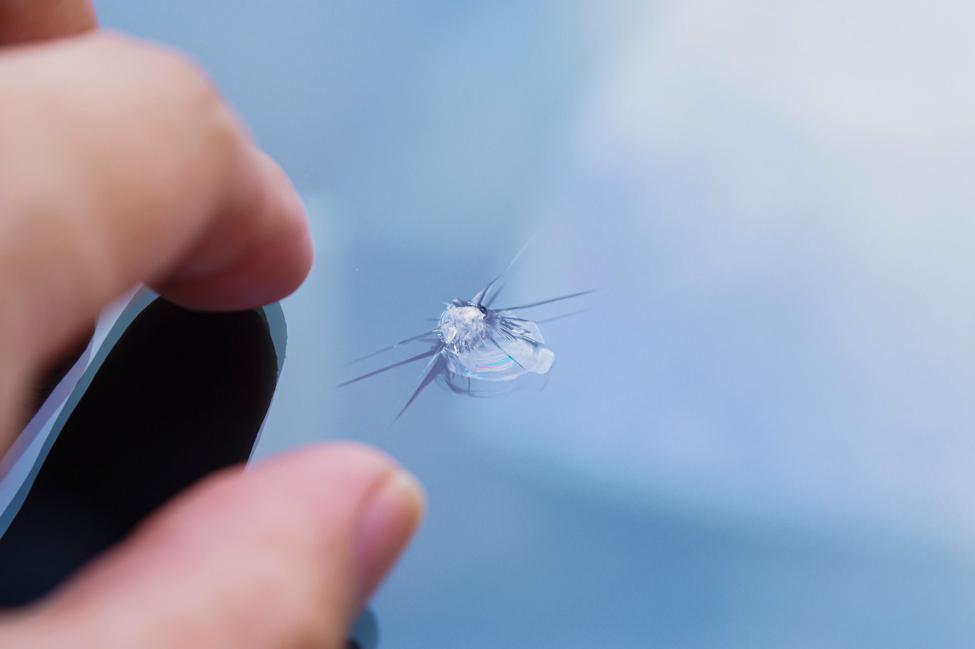 A person is holding a cracked windshield in their hand.
