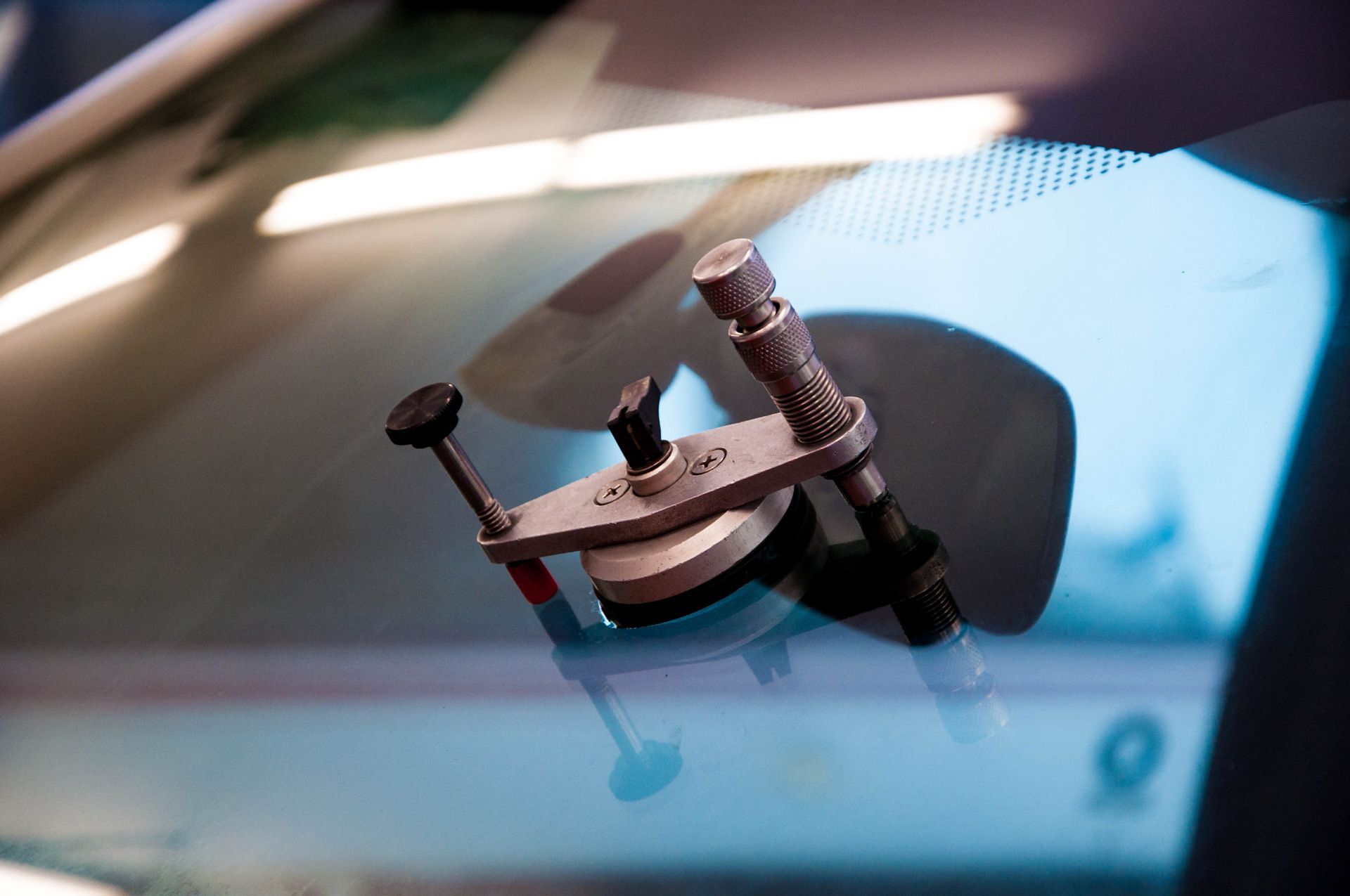 A close up of a windshield repair tool on a car windshield.