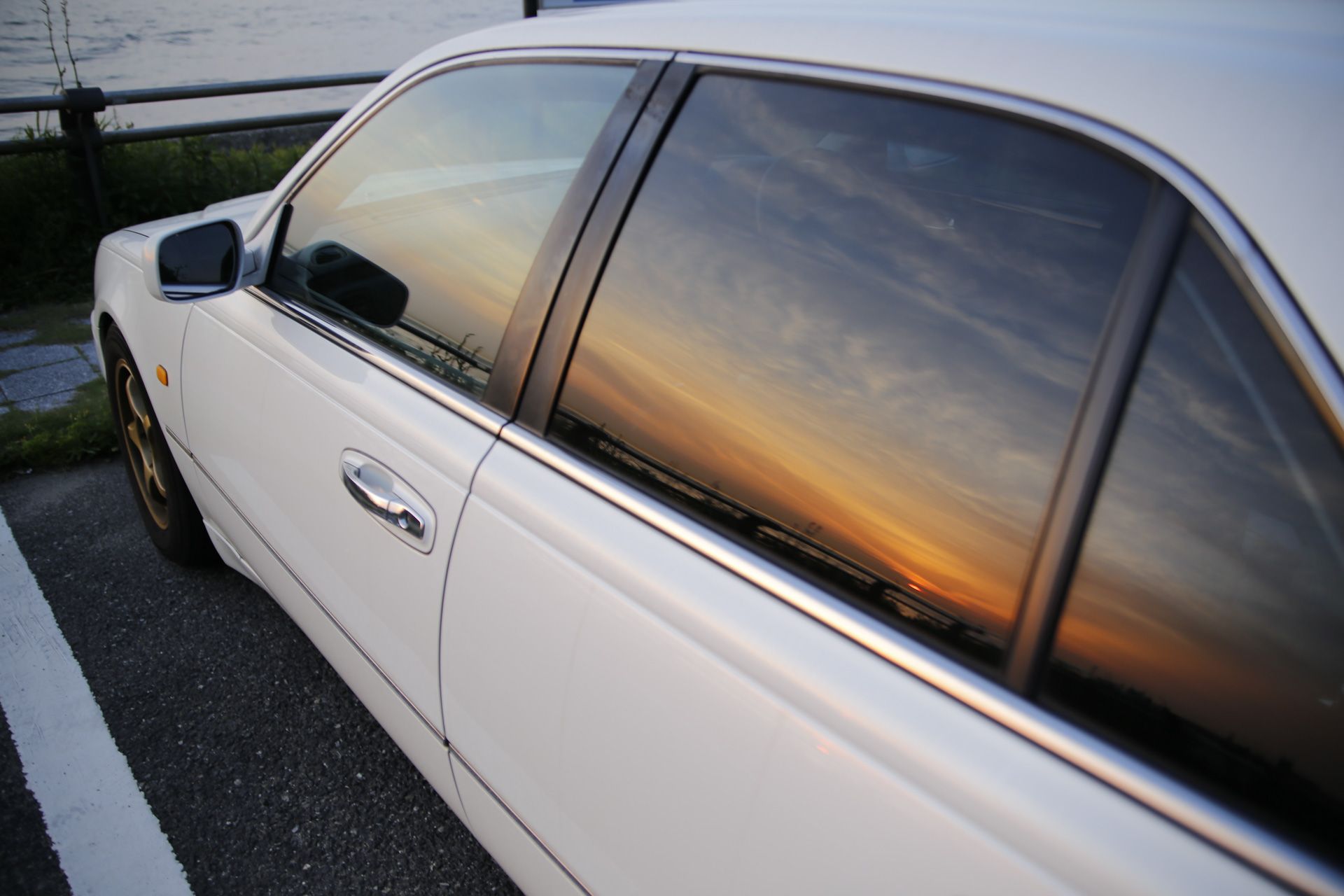 A white car is parked next to a body of water