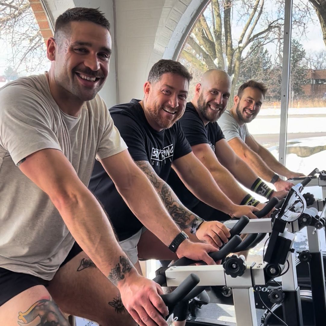 A group of men are riding exercise bikes in a gym.