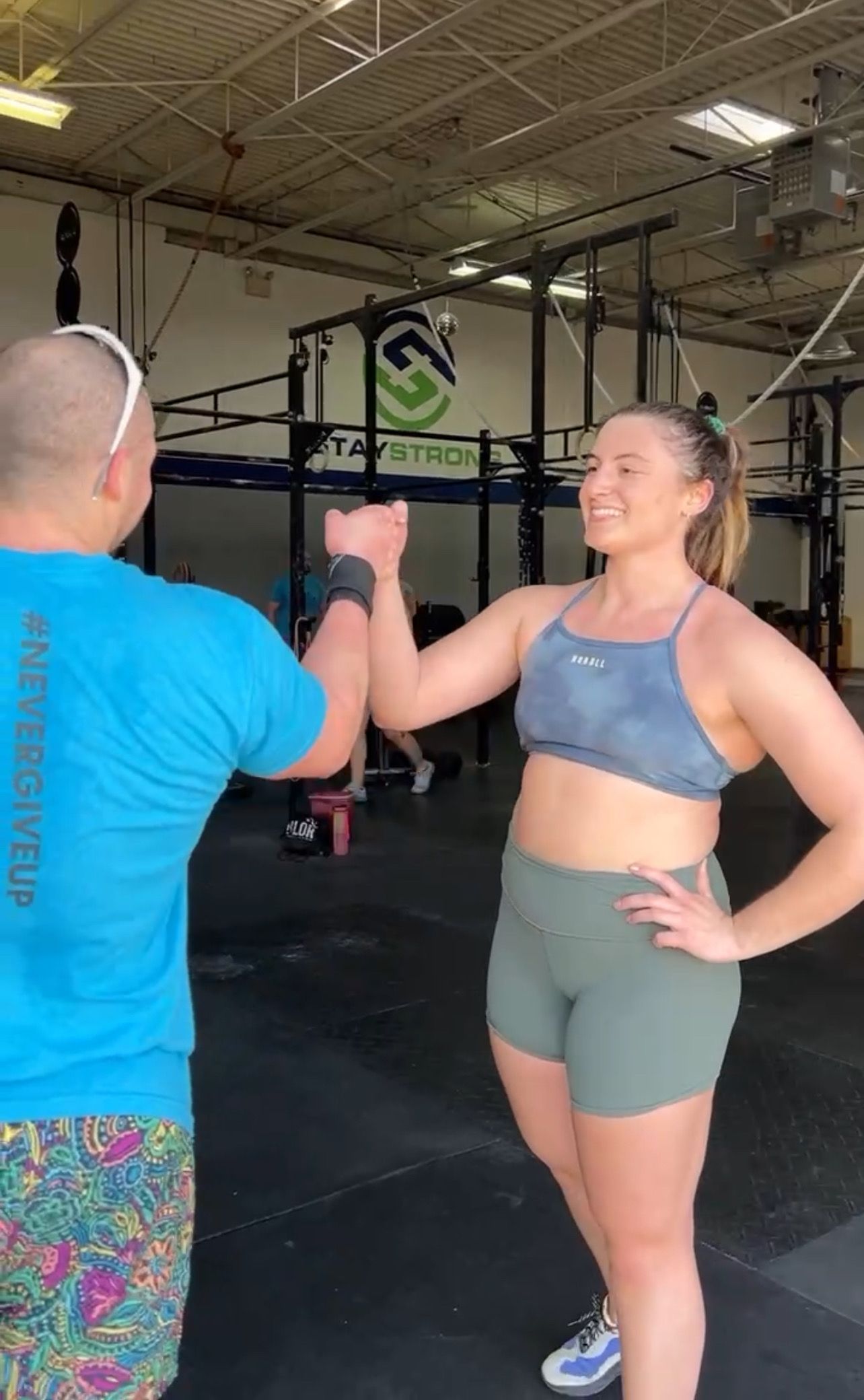A man and a woman are giving each other a high five in a gym.