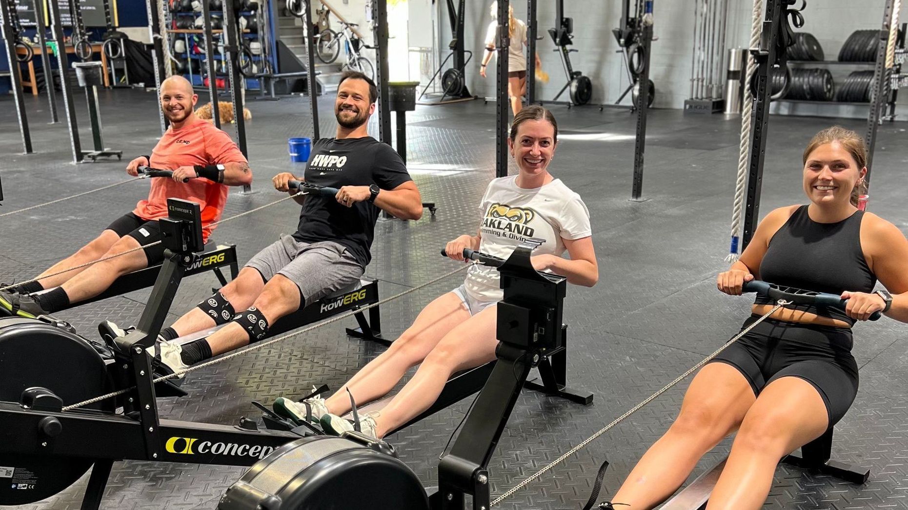 A group of people are rowing rowing machines in a gym.