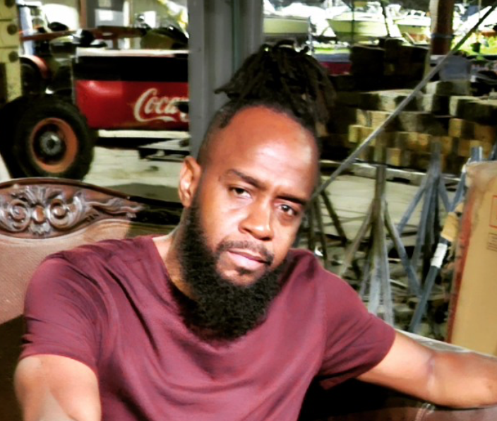 A man with a beard is sitting in front of a coca cola truck