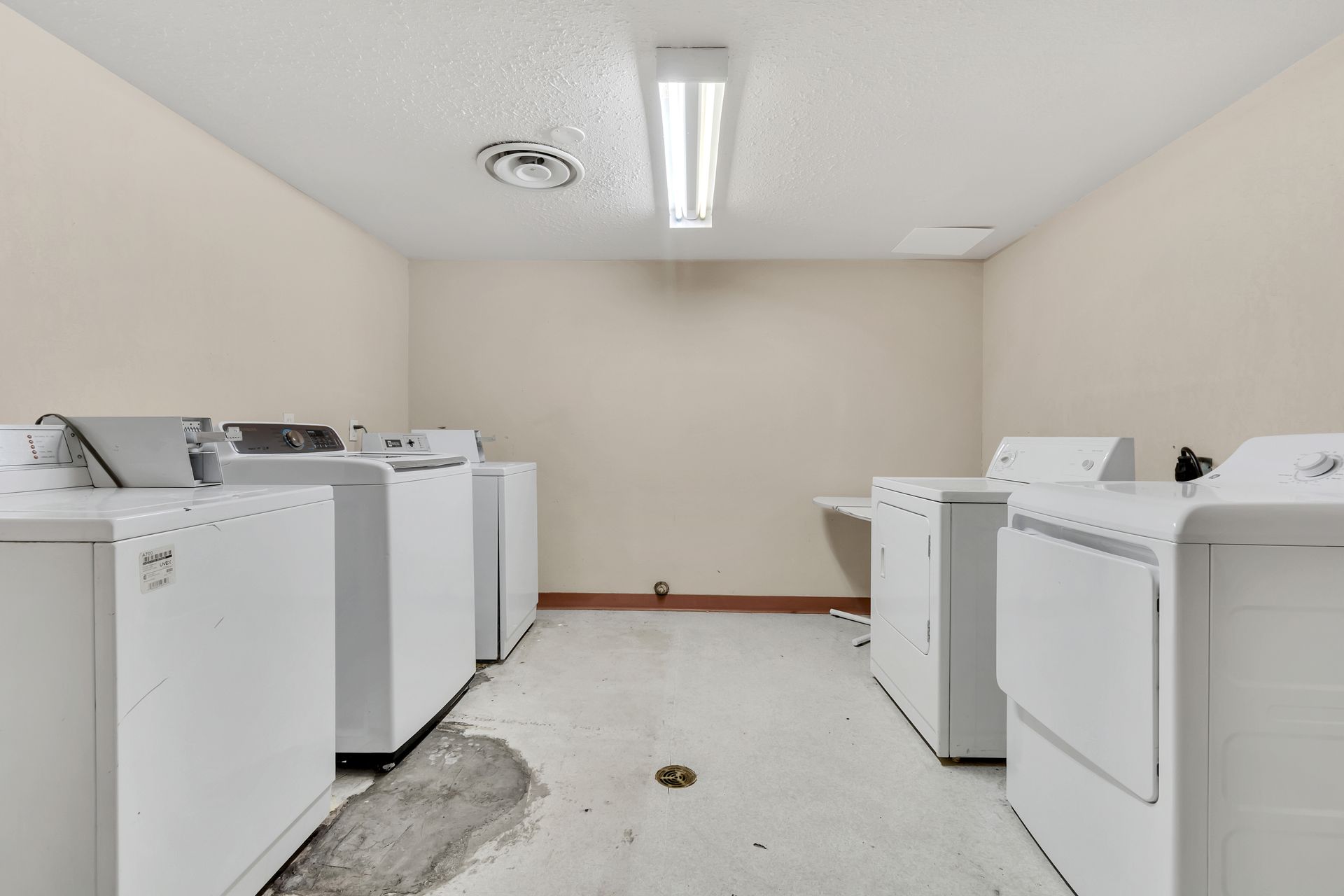 A laundry room with a lot of white washers and dryers