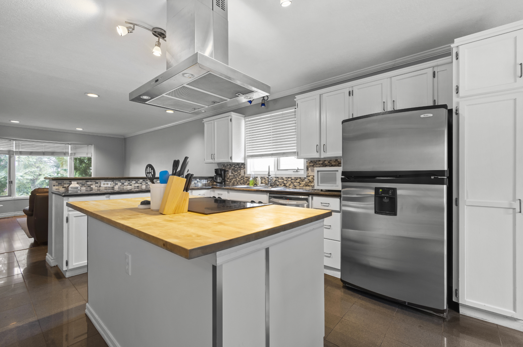 Bright, modern kitchen with white cabinets, stainless steel appliances, and a butcher block island.