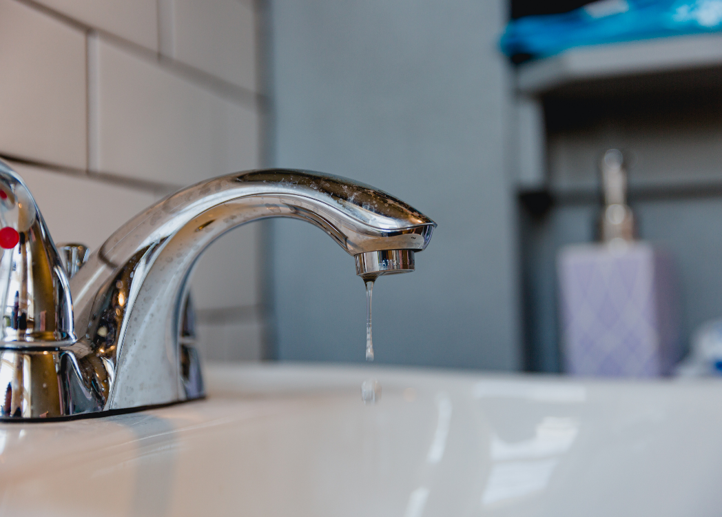 Dripping kitchen faucet close-up with water pooling