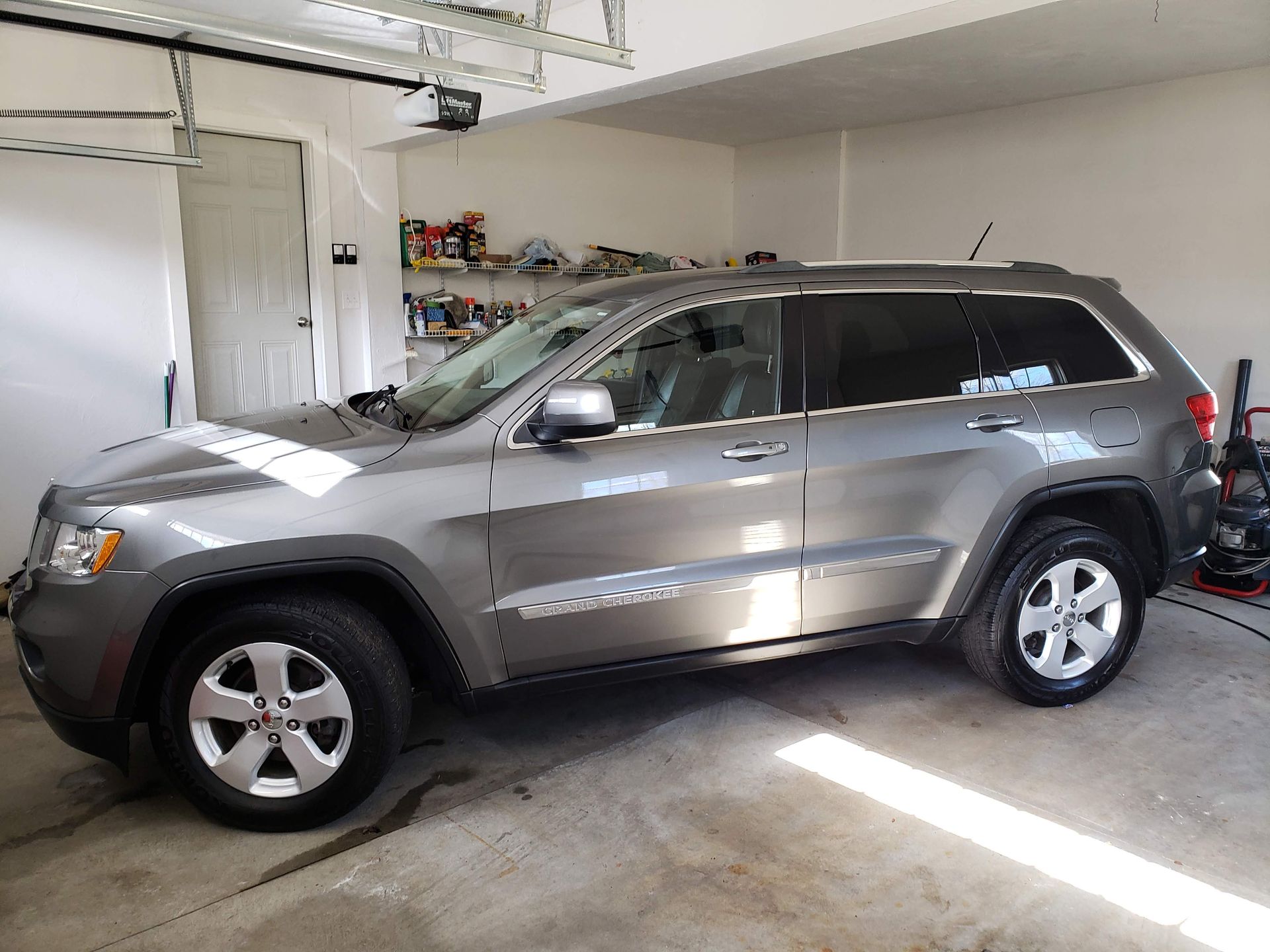 A gray jeep grand cherokee is parked in a garage.
