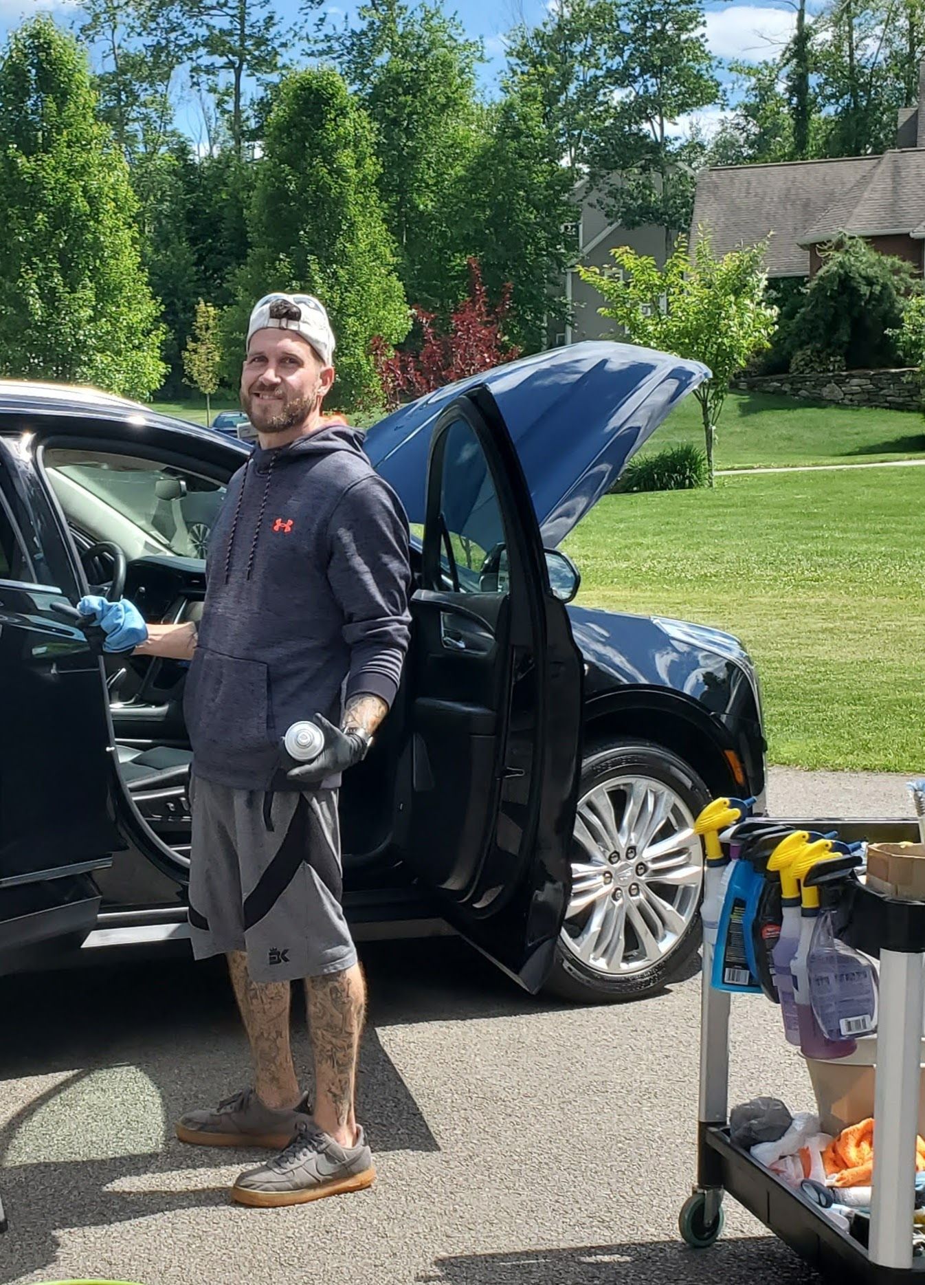 A man is standing next to a car with the trunk open.