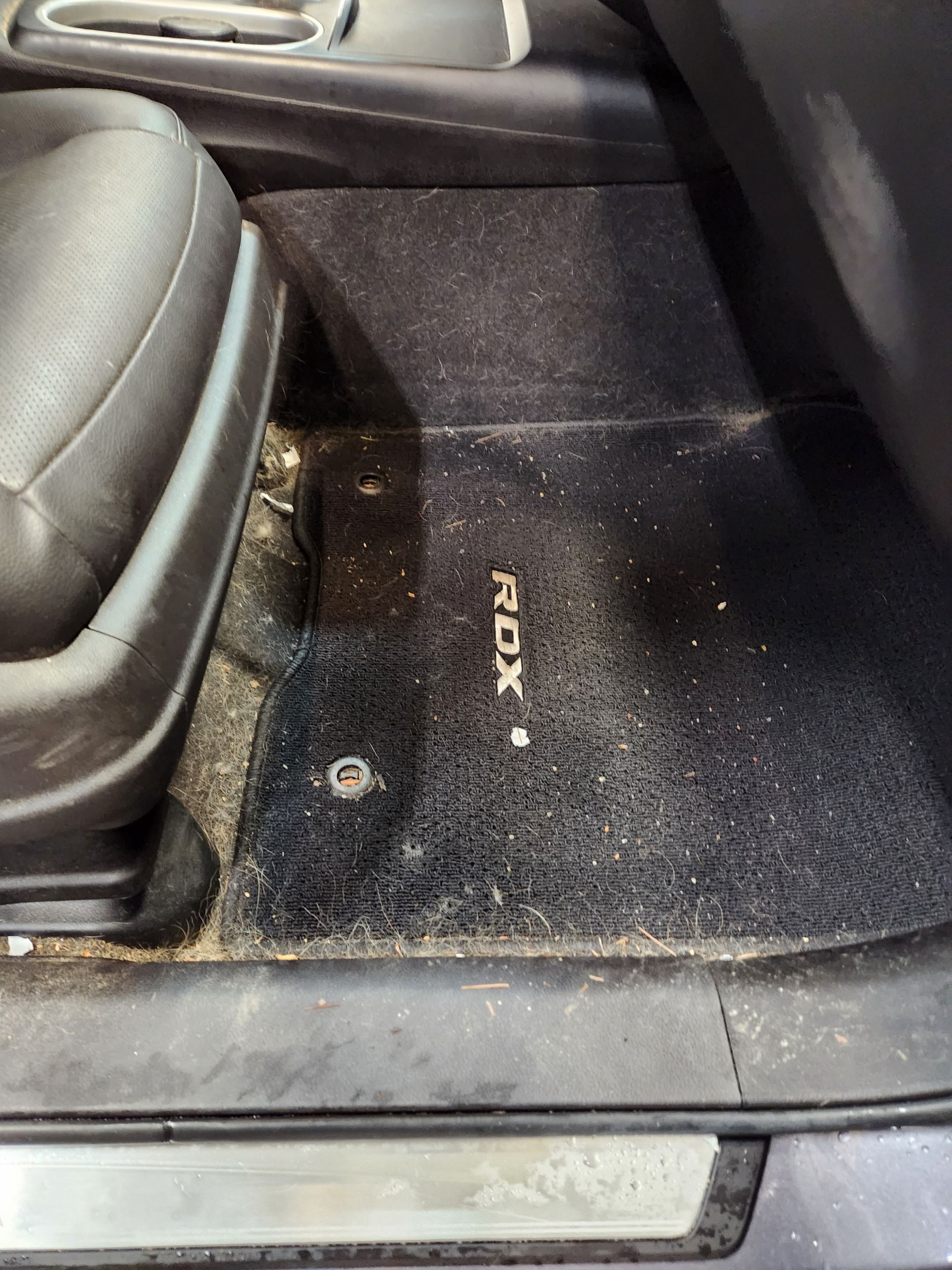 A close up of a dirty floor mat in a car.