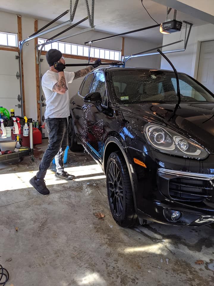 A man is standing next to a black car in a garage.