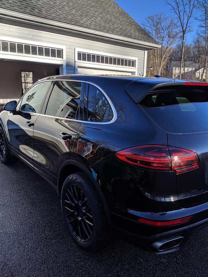 A black porsche cayenne is parked in front of a garage.