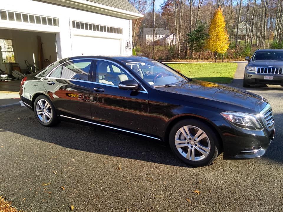 A black mercedes benz is parked in front of a garage.