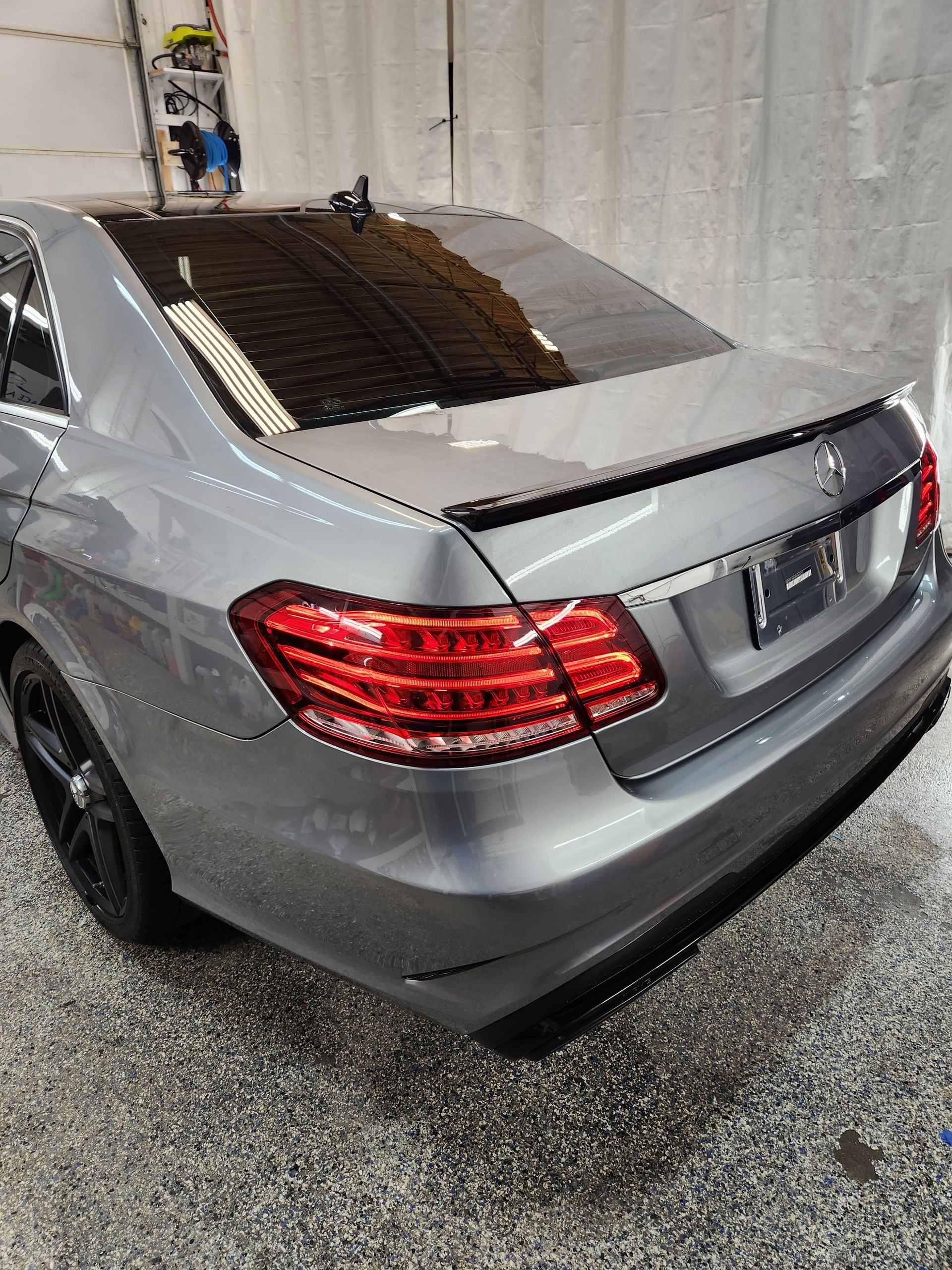 A silver mercedes benz e class is parked in a garage.