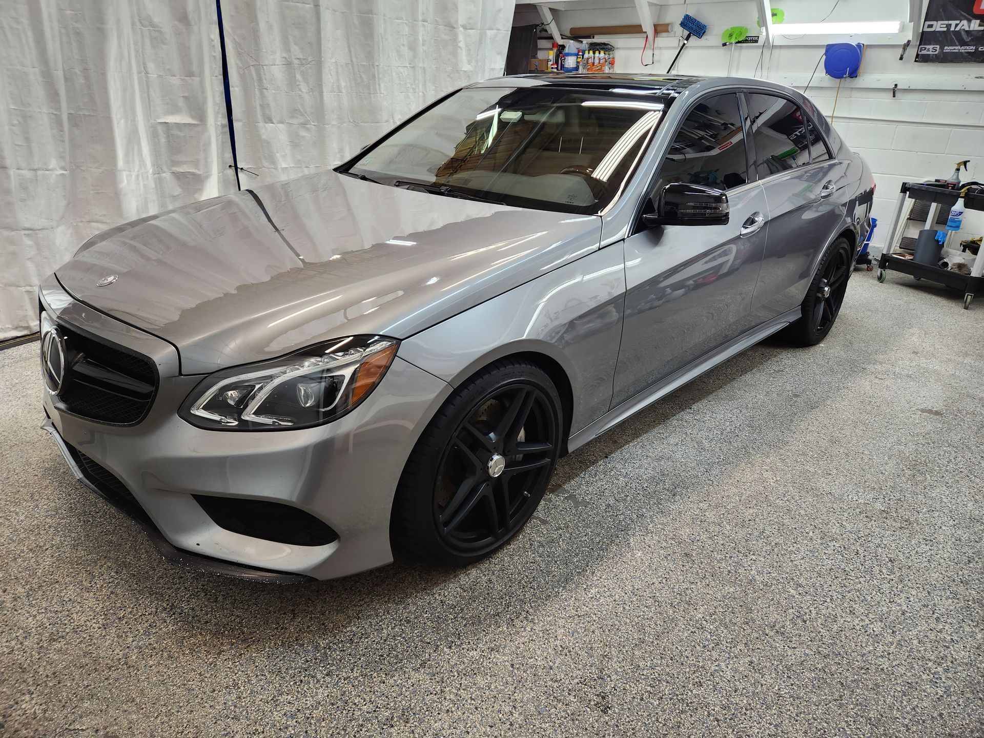 A silver mercedes benz e class is parked in a garage.