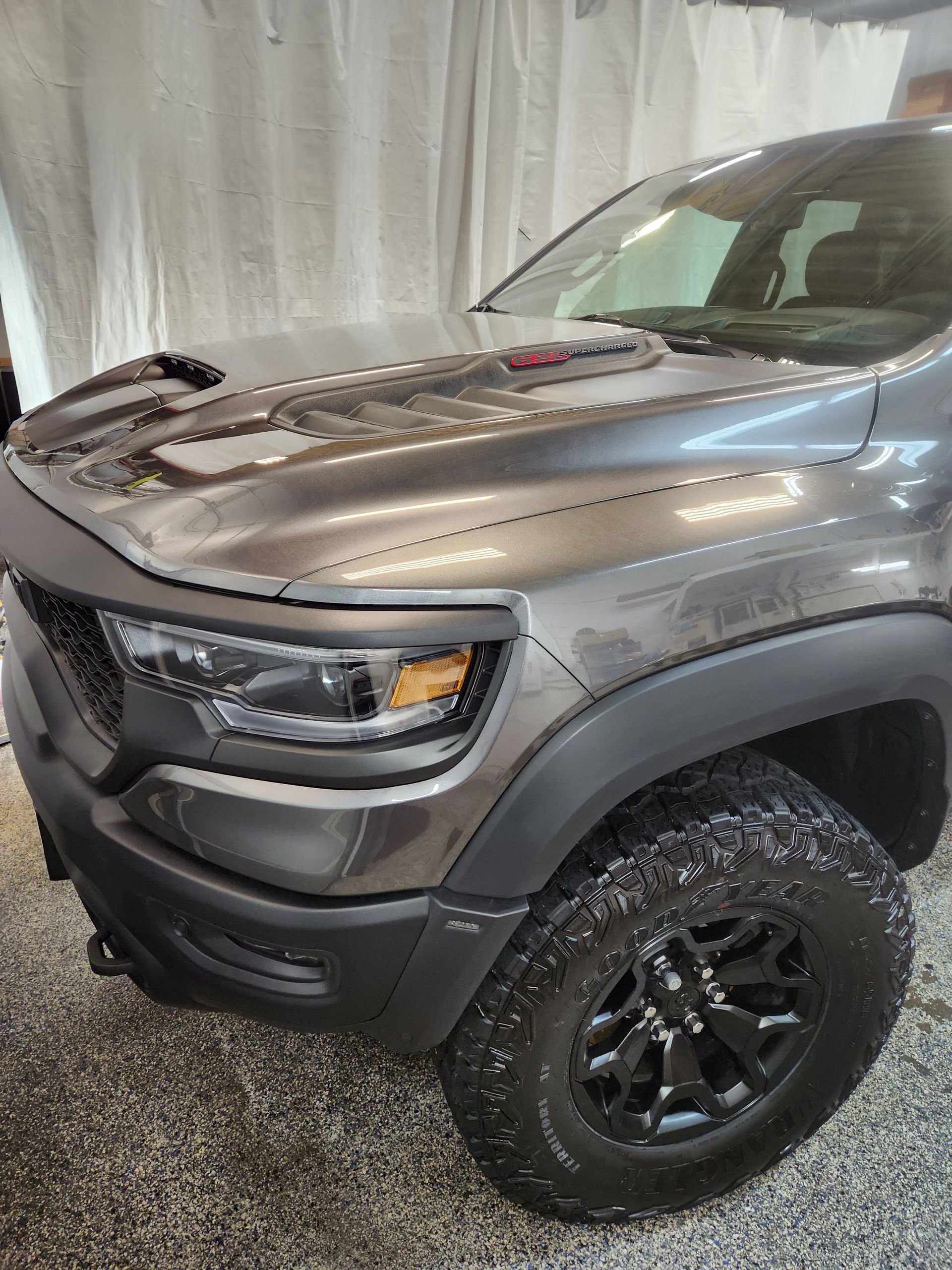 A ram truck is parked in a garage with the hood up.