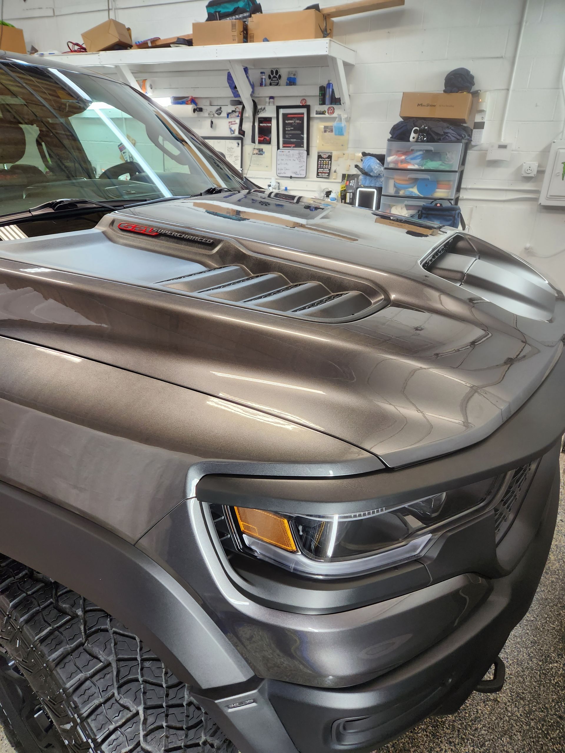 A ram truck is parked in a garage with the hood up.