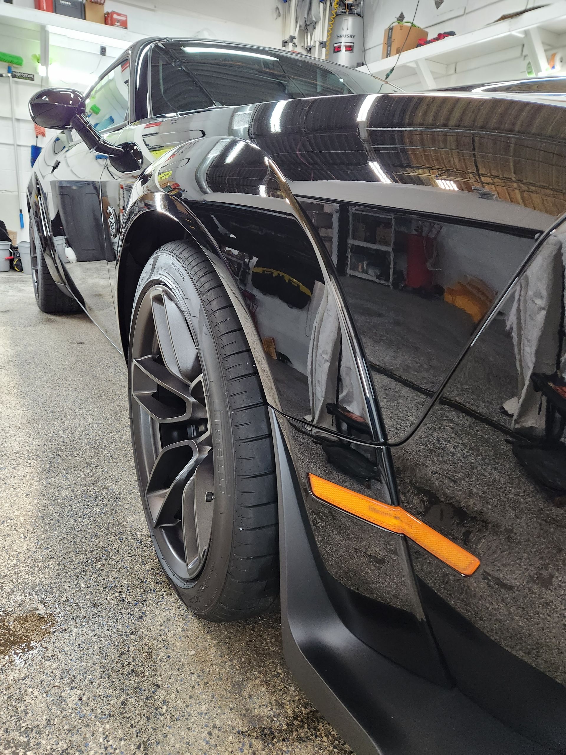 A black sports car is parked in a garage.