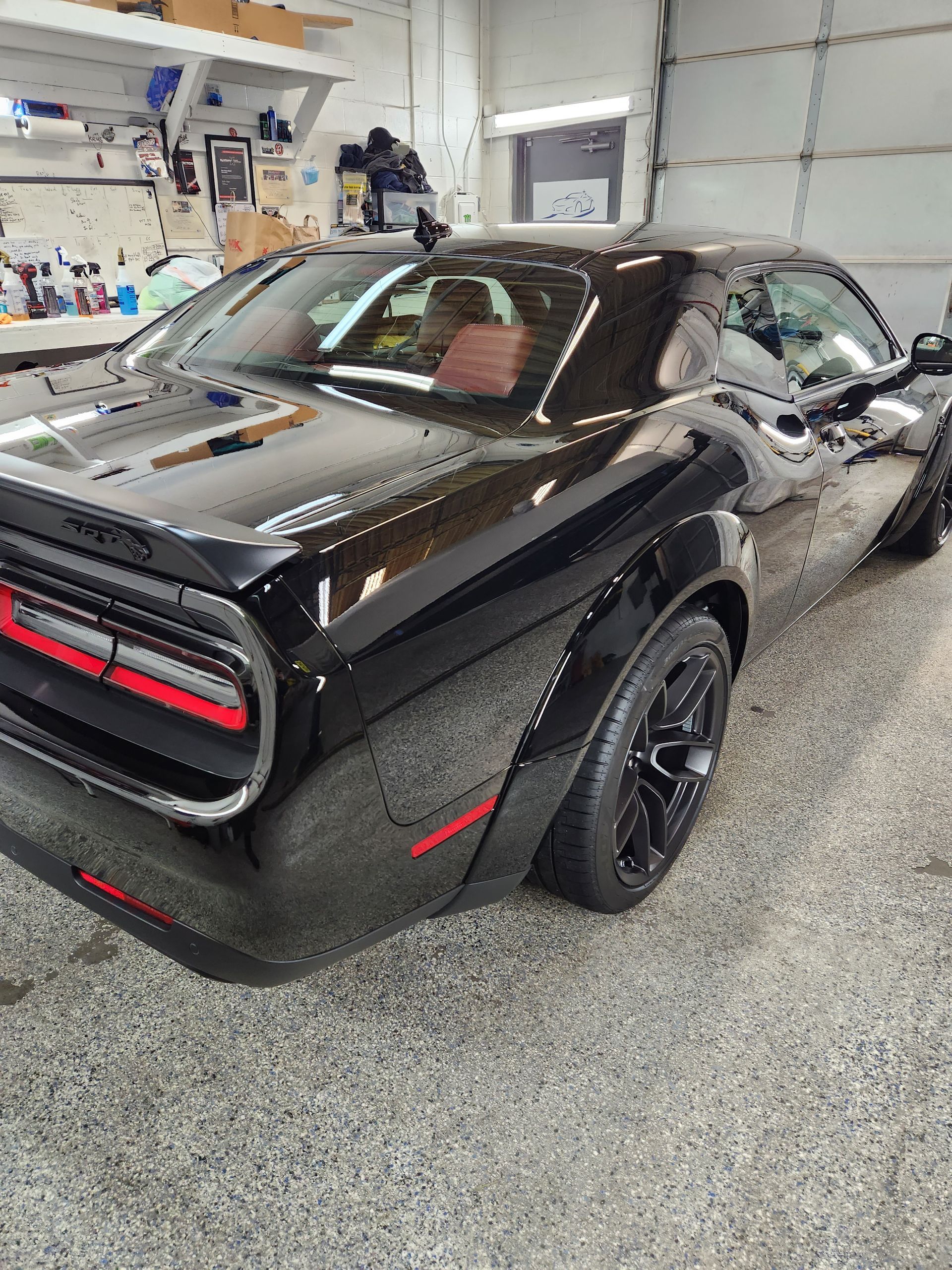 A black dodge challenger is parked in a garage.