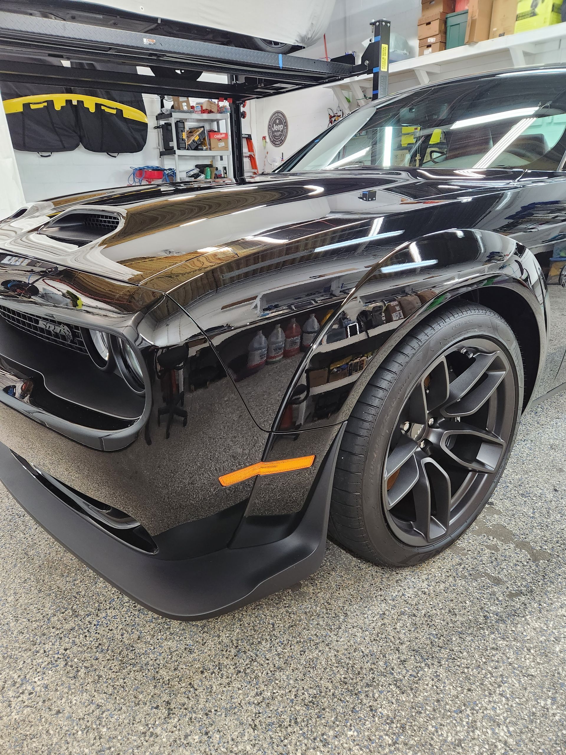 A black dodge challenger is parked in a garage.