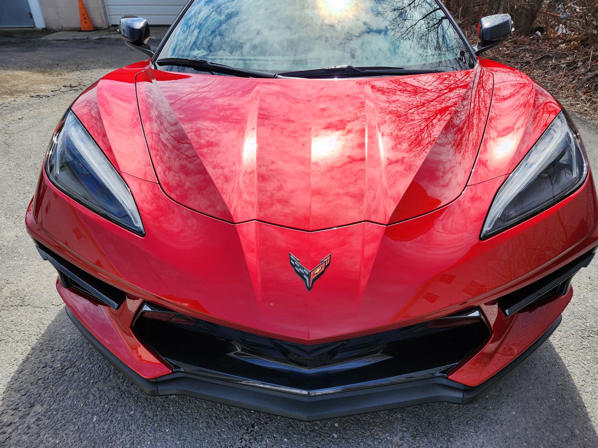 A red corvette is parked in a driveway next to a garage.