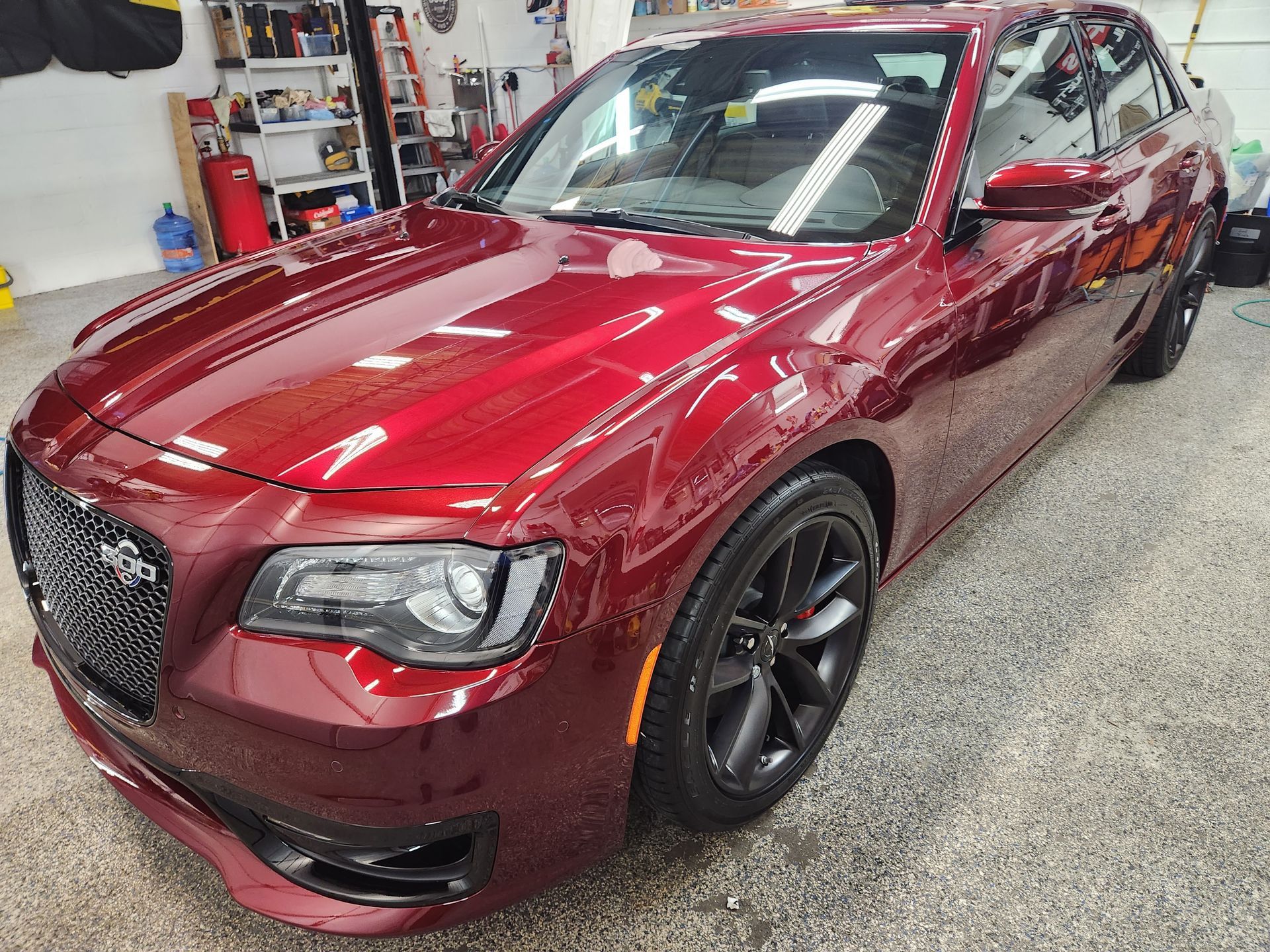 A red chrysler 300 is parked in a garage.