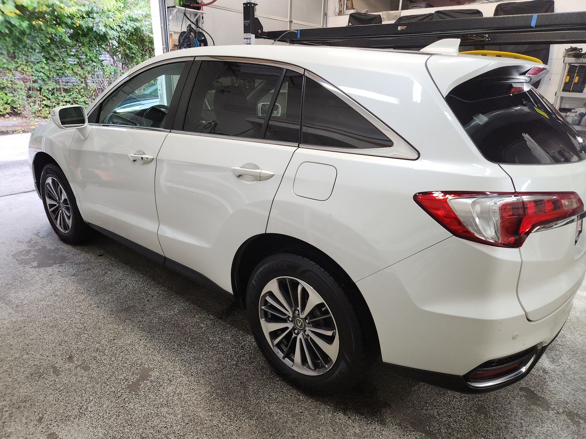 A white suv with a roof rack is parked in a garage.