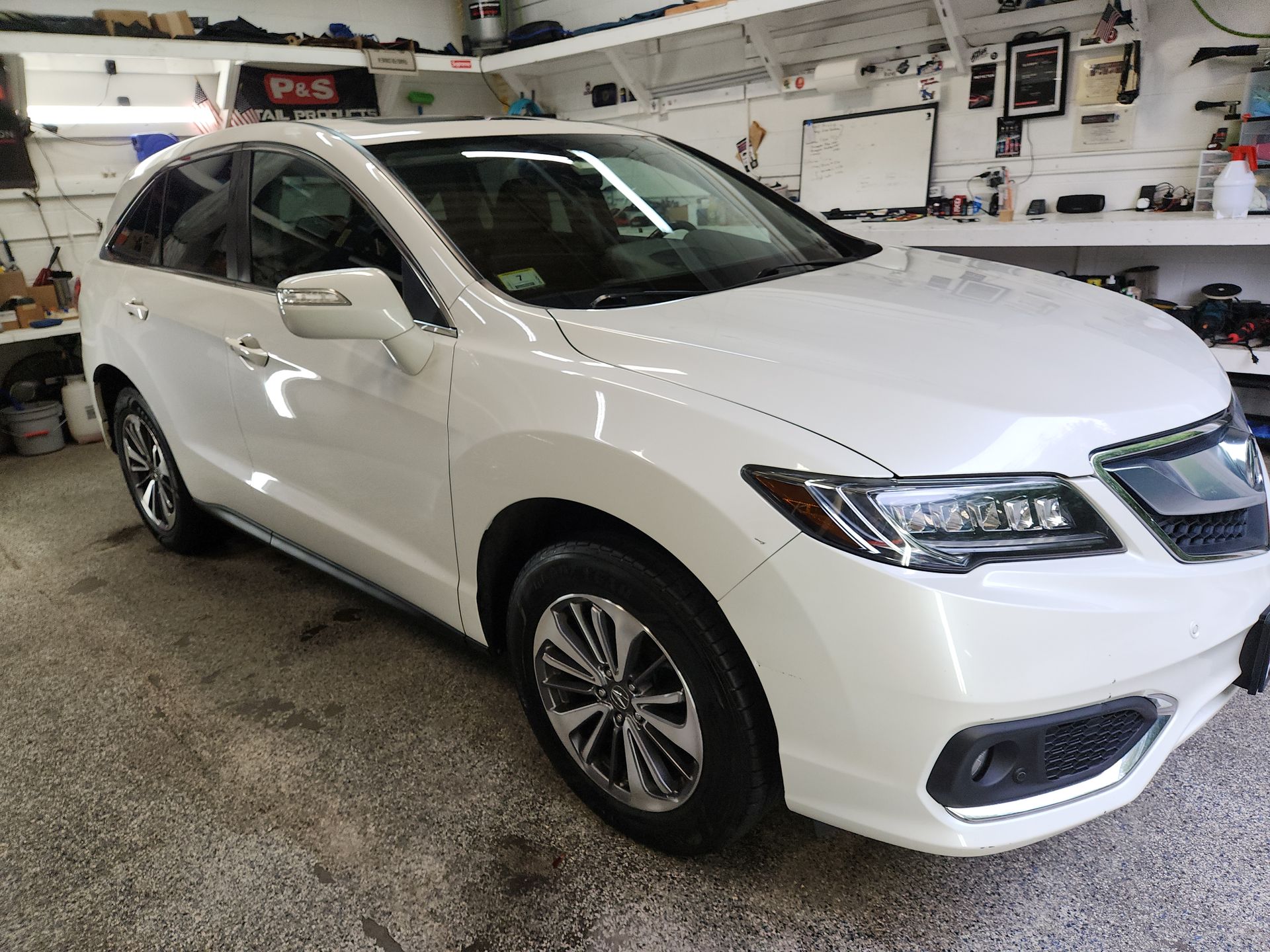 A white honda ridgeline is parked in a garage.
