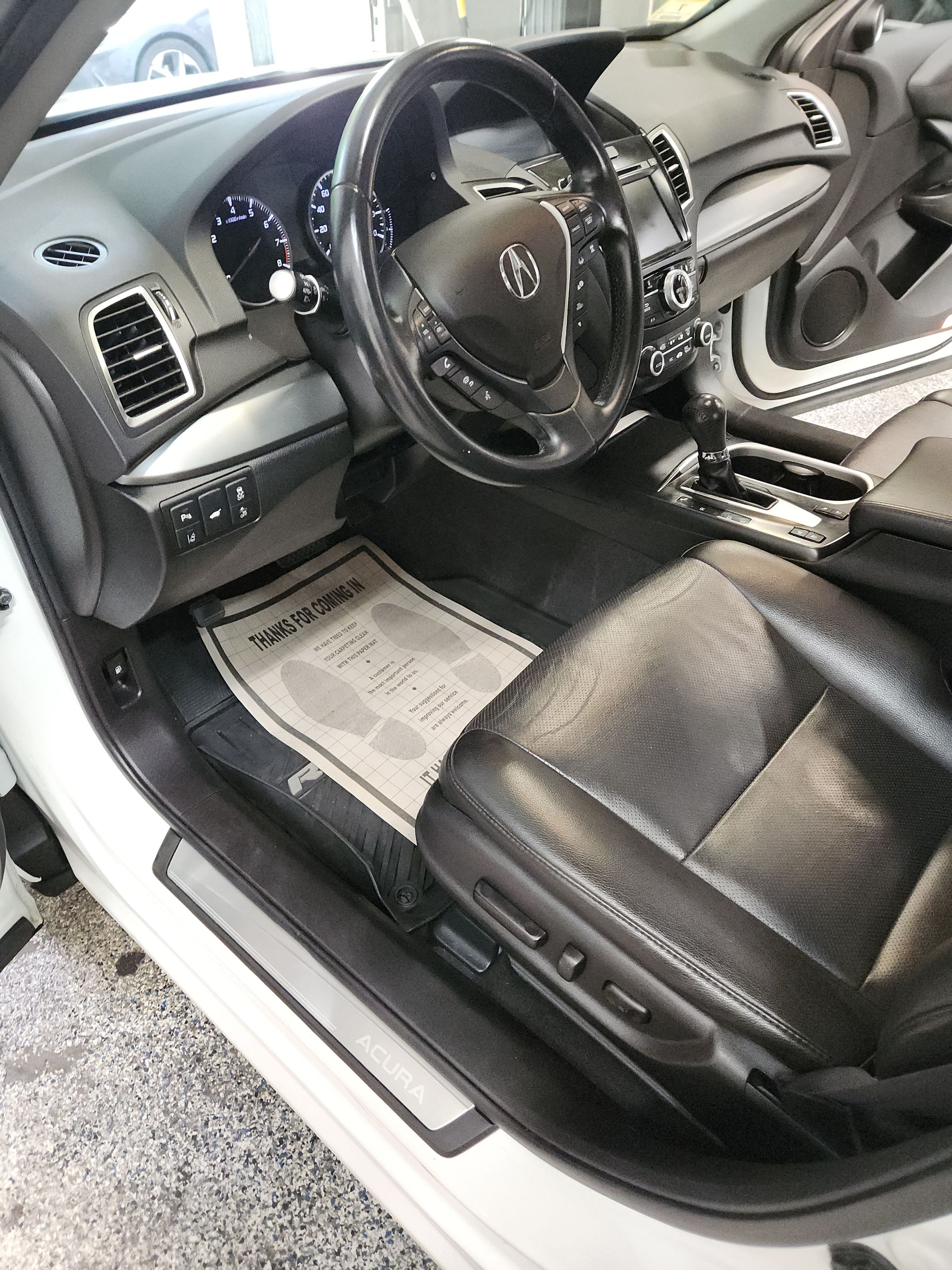 The interior of a white car with black seats and a steering wheel.