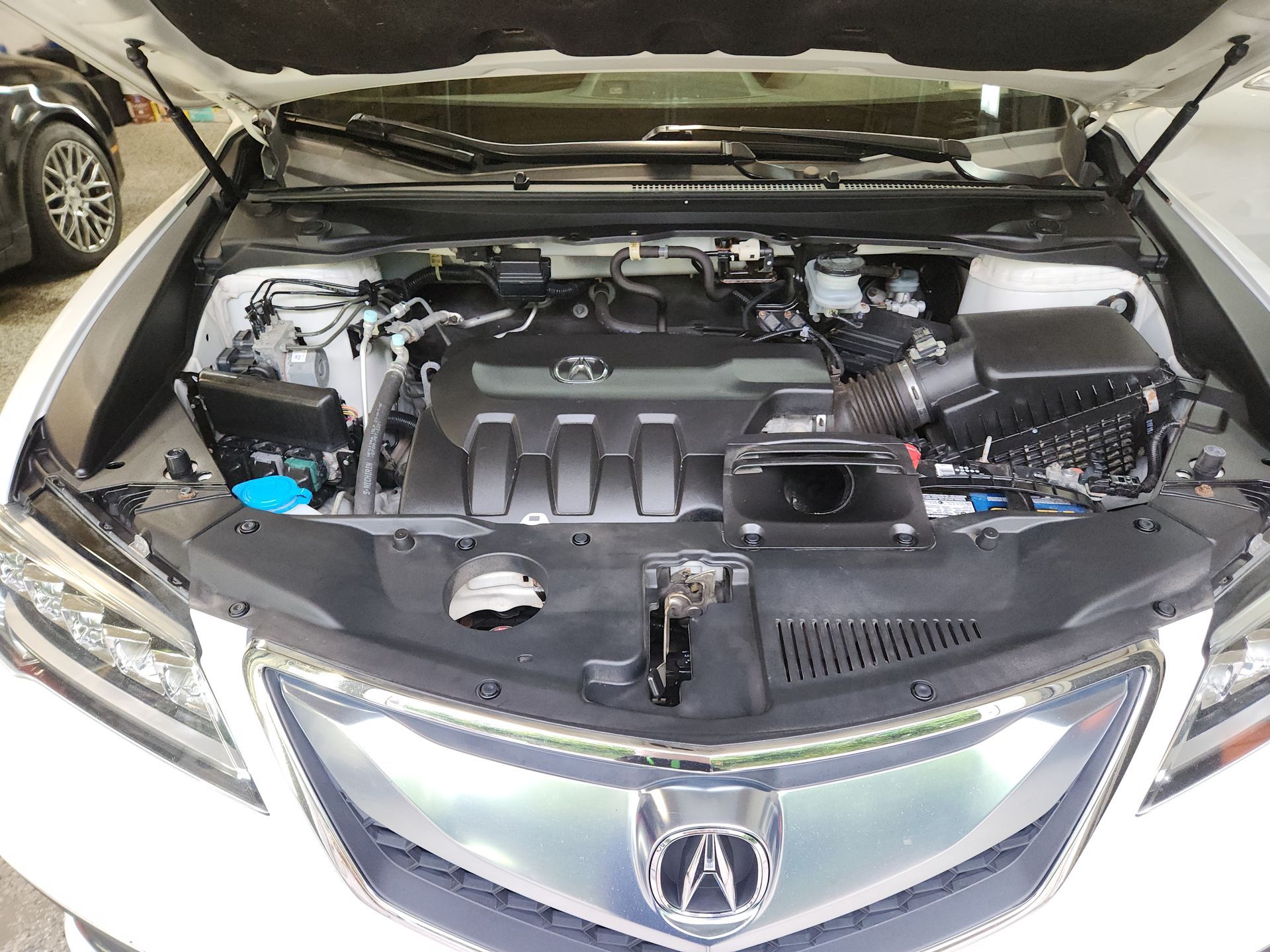The engine of a white acura integra is shown with the hood open.
