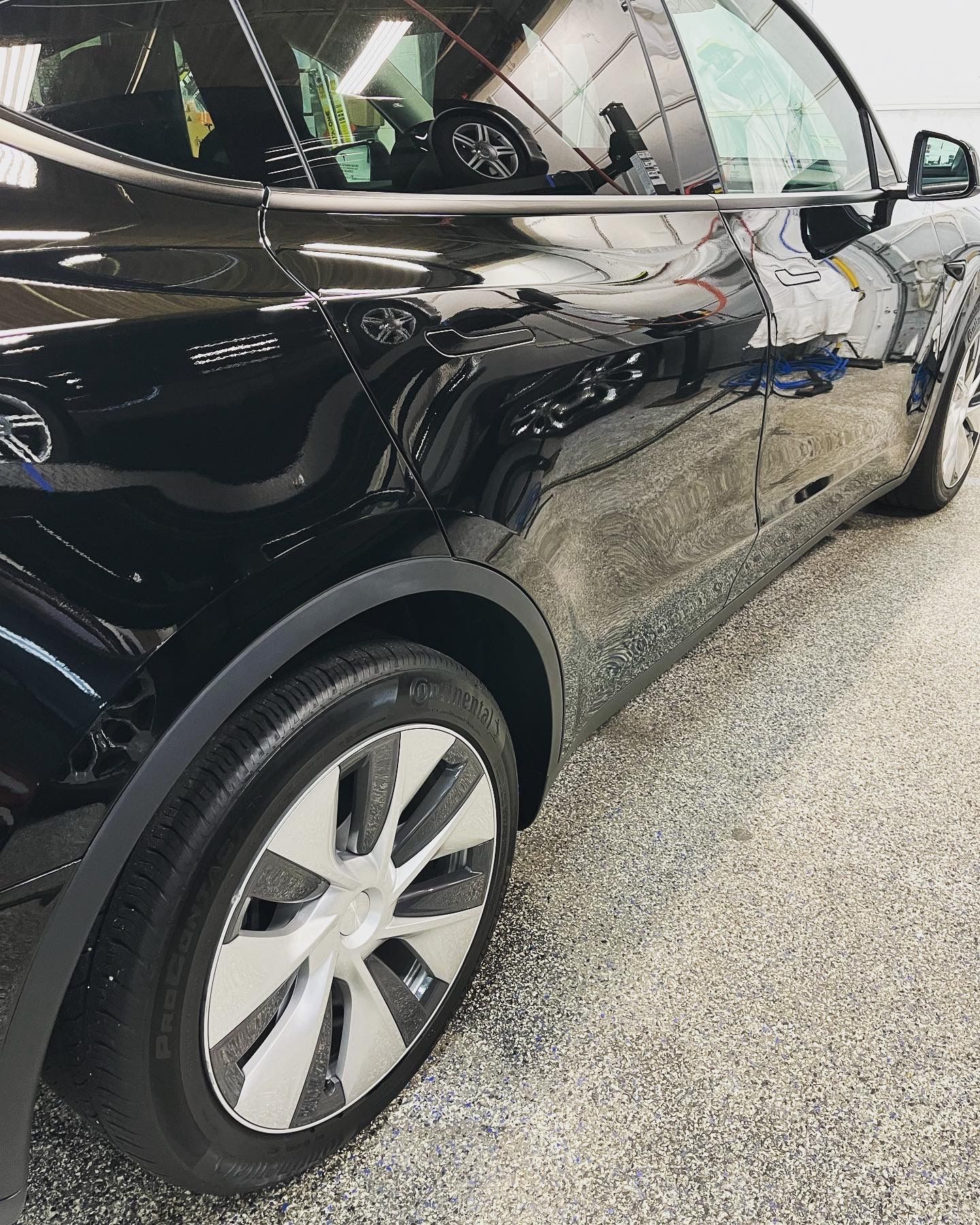 A black car with white wheels is parked in a garage.