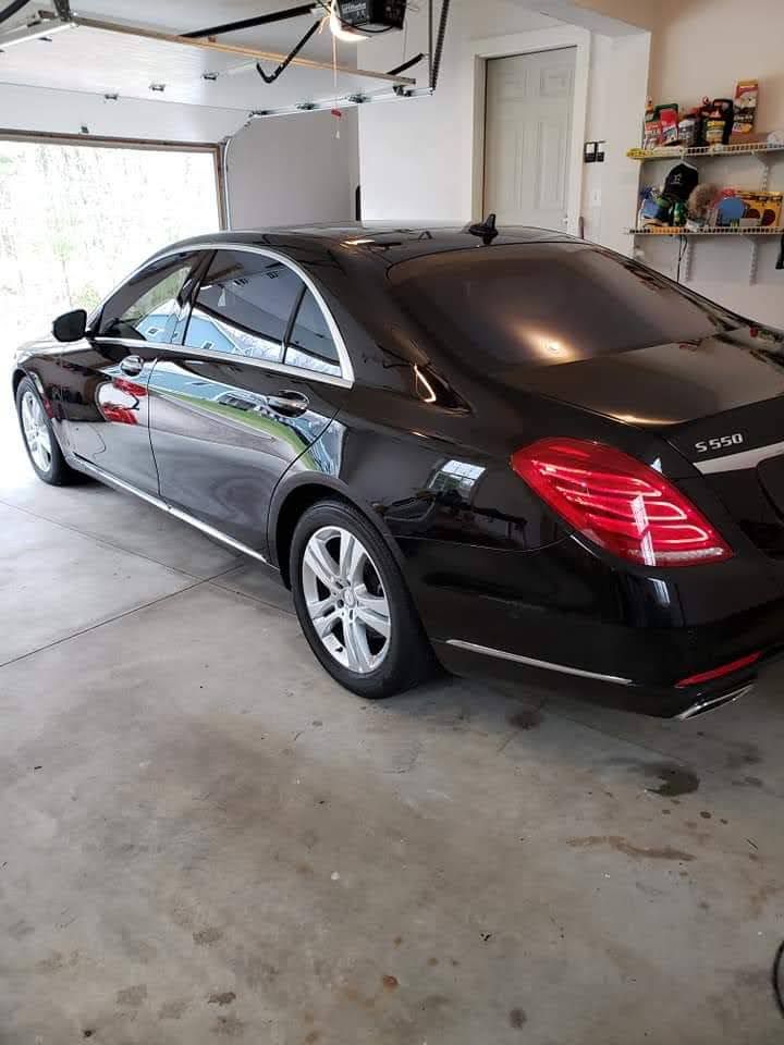 A black mercedes benz s class is parked in a garage.
