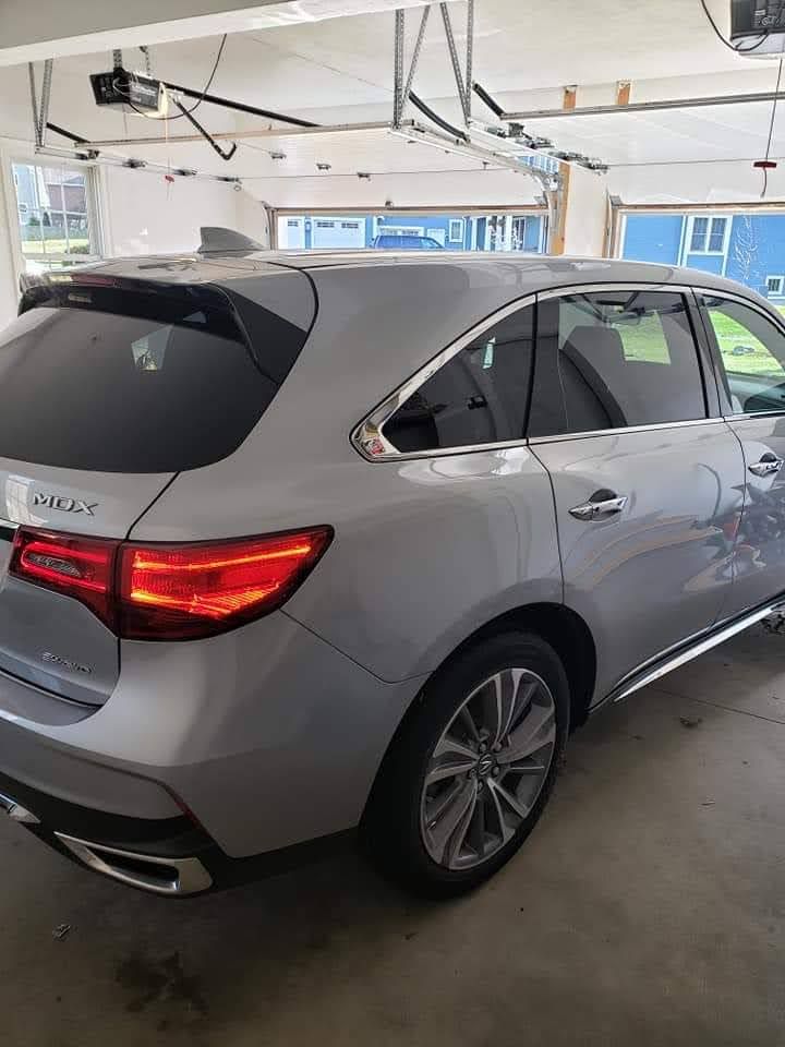 A silver acura mdx is parked in a garage.