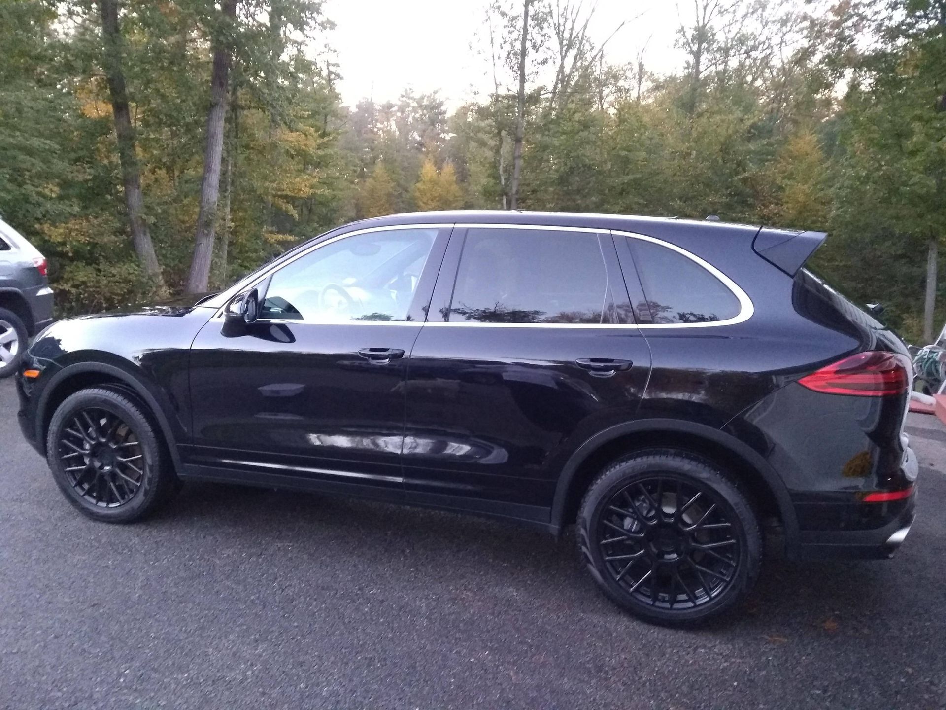 A black porsche cayenne is parked on the side of the road.
