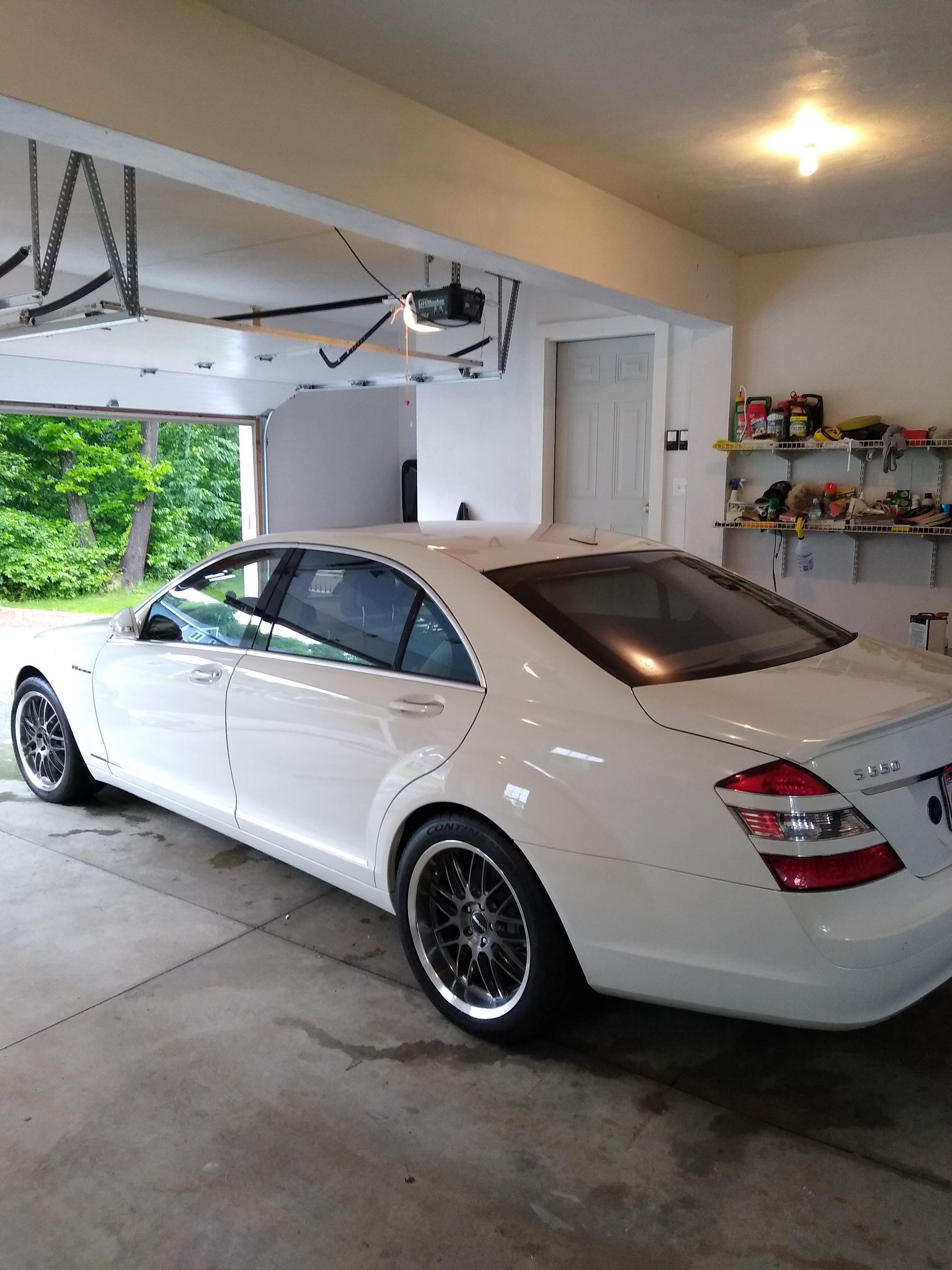 A white car is parked in a garage with a garage door open.