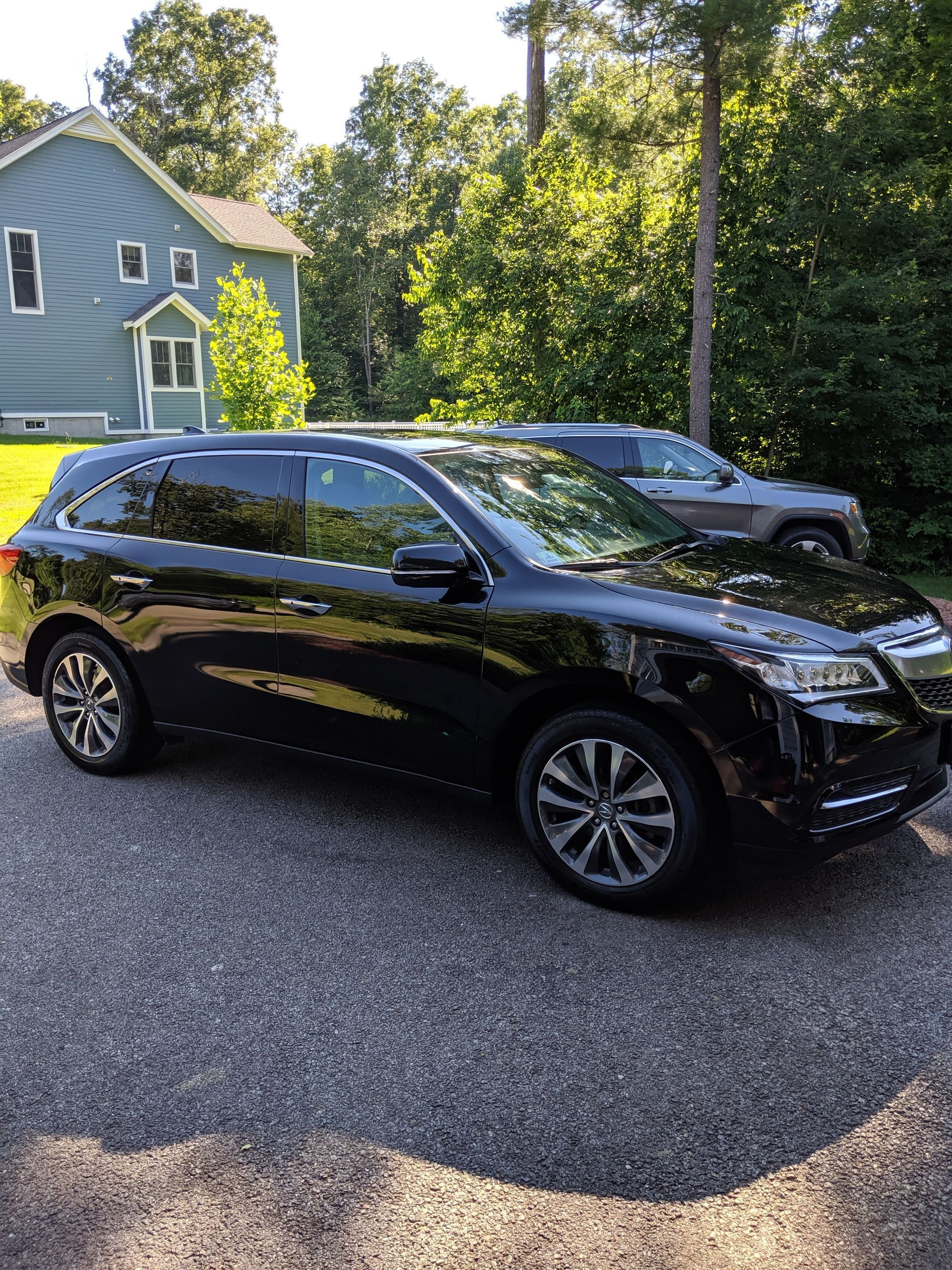 A black suv is parked in a driveway in front of a house.