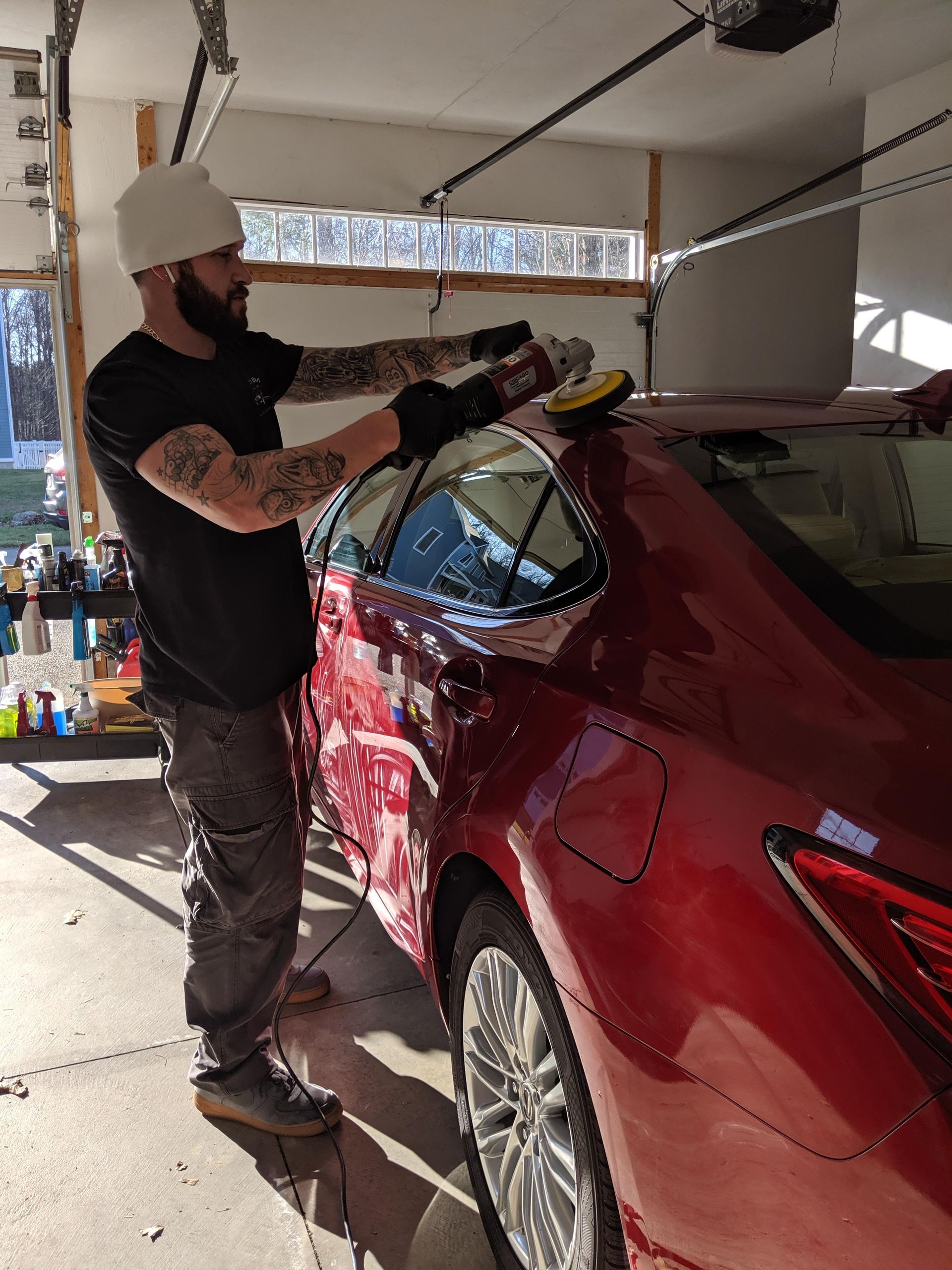 A man is polishing a red car in a garage.