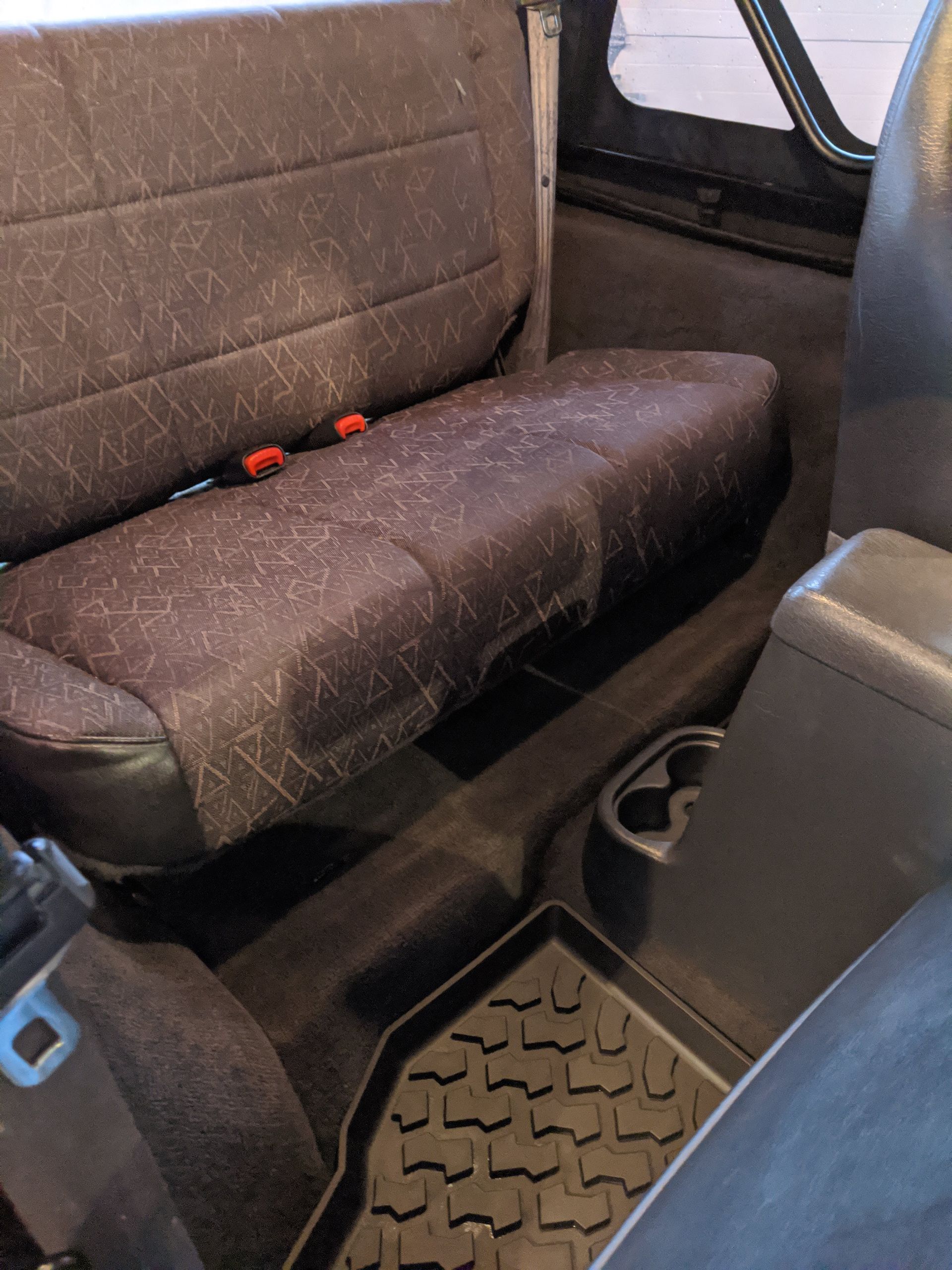 The back seat of a car with a seat cover on it.