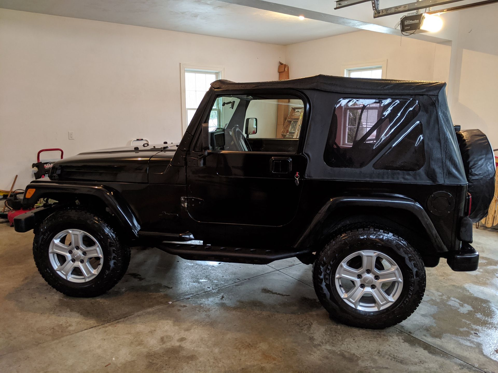 A black jeep is parked in a garage.